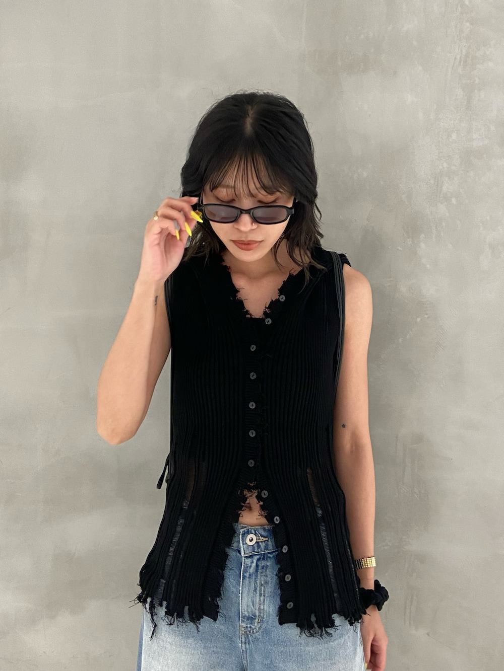 ブラック系のニット/セーター、ブルー系のデニムパンツ、ブラック系のブーツを着用したレディースの夏コーディネートの2枚目の写真