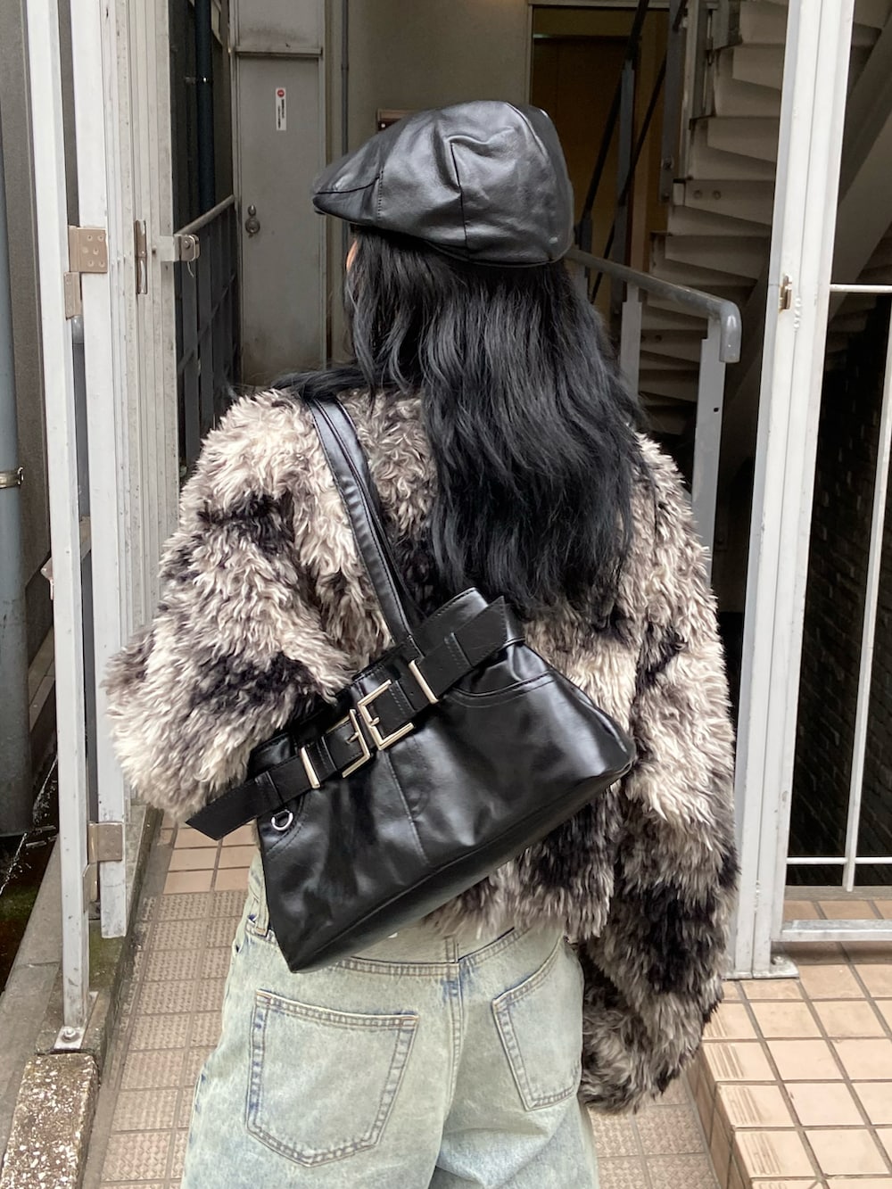 ブラック系のブルゾン、ブルー系のデニムパンツ、ブラック系のショルダーバッグを着用したレディースの秋コーディネートの4枚目の写真