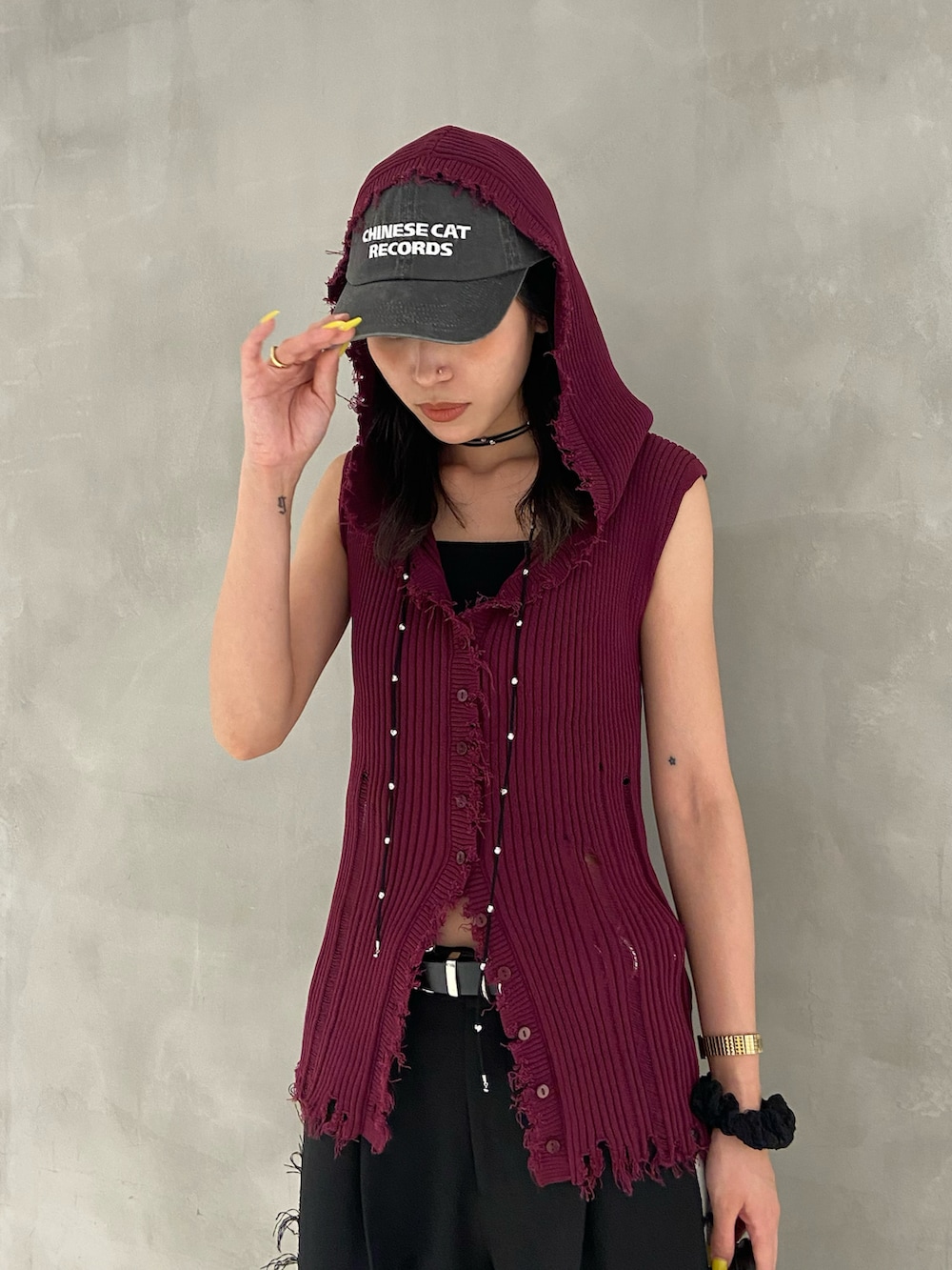 レッド系のニット/セーター、ブラック系のスラックス、ブラック系のスニーカーを着用したレディースの夏コーディネートの2枚目の写真