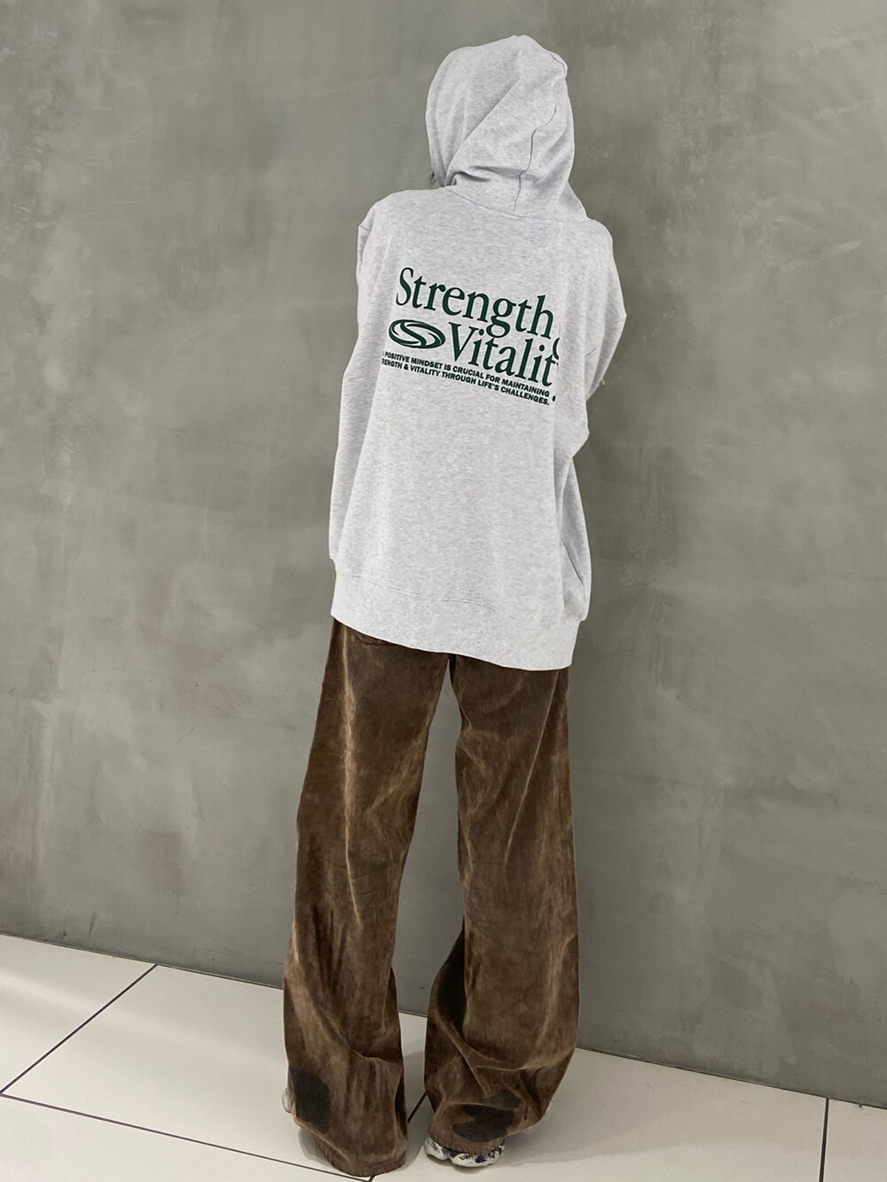 ホワイト系のパーカー、ブラウン系のデニムパンツ、ブラック系のスニーカーを着用したレディースの秋コーディネートの2枚目の写真