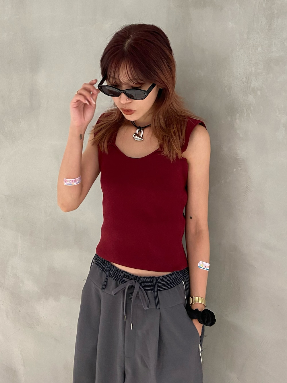 レッド系のタンクトップ、グレー系のスラックス、ブラック系のローファーを着用したレディースの夏コーディネートの2枚目の写真