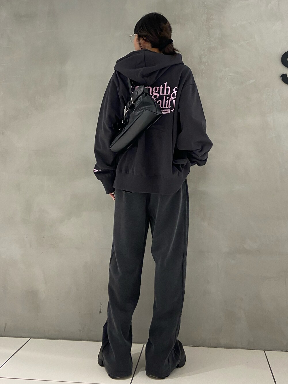 ブラック系のパーカー、ブラック系のスウェットパンツ、ブラック系のブーツを着用したレディースの秋コーディネートの2枚目の写真