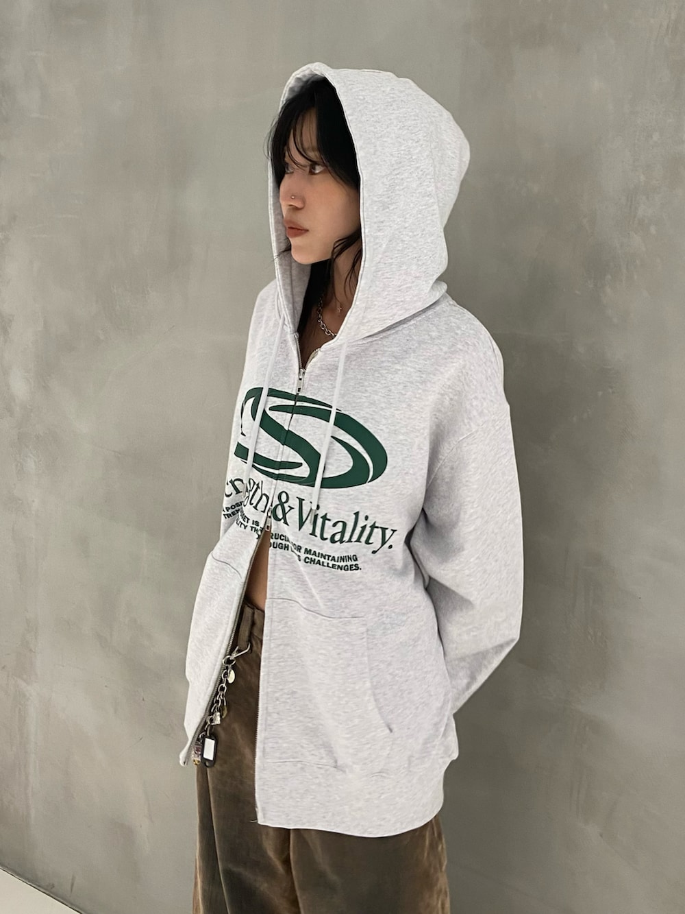 ホワイト系のパーカー、ブラウン系のデニムパンツ、ブラック系のスニーカーを着用したレディースの秋コーディネートの3枚目の写真