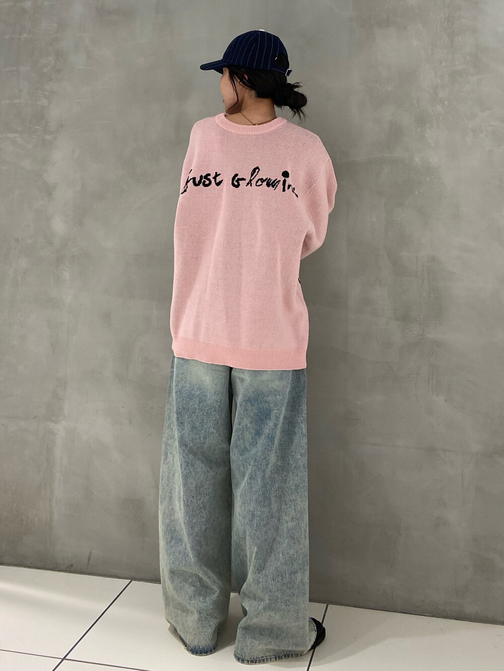 ピンク系のニット/セーター、ブルー系のデニムパンツ、ブルー系のキャップを着用したレディースの秋コーディネートの2枚目の写真