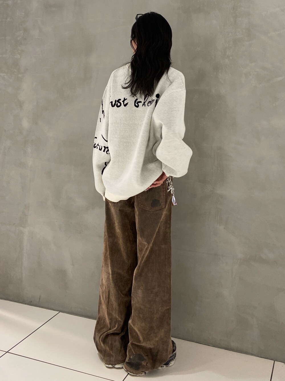 ホワイト系のニット/セーター、ブラウン系のデニムパンツ、ブラック系のスニーカーを着用したレディースの秋コーディネートの2枚目の写真