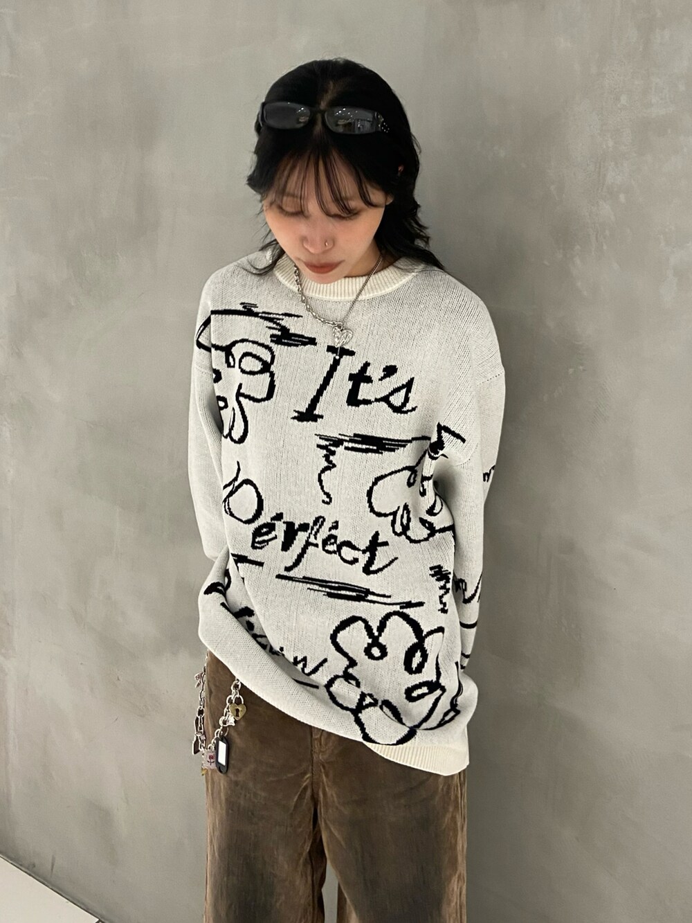 ホワイト系のニット/セーター、ブラウン系のデニムパンツ、ブラック系のスニーカーを着用したレディースの秋コーディネートの3枚目の写真