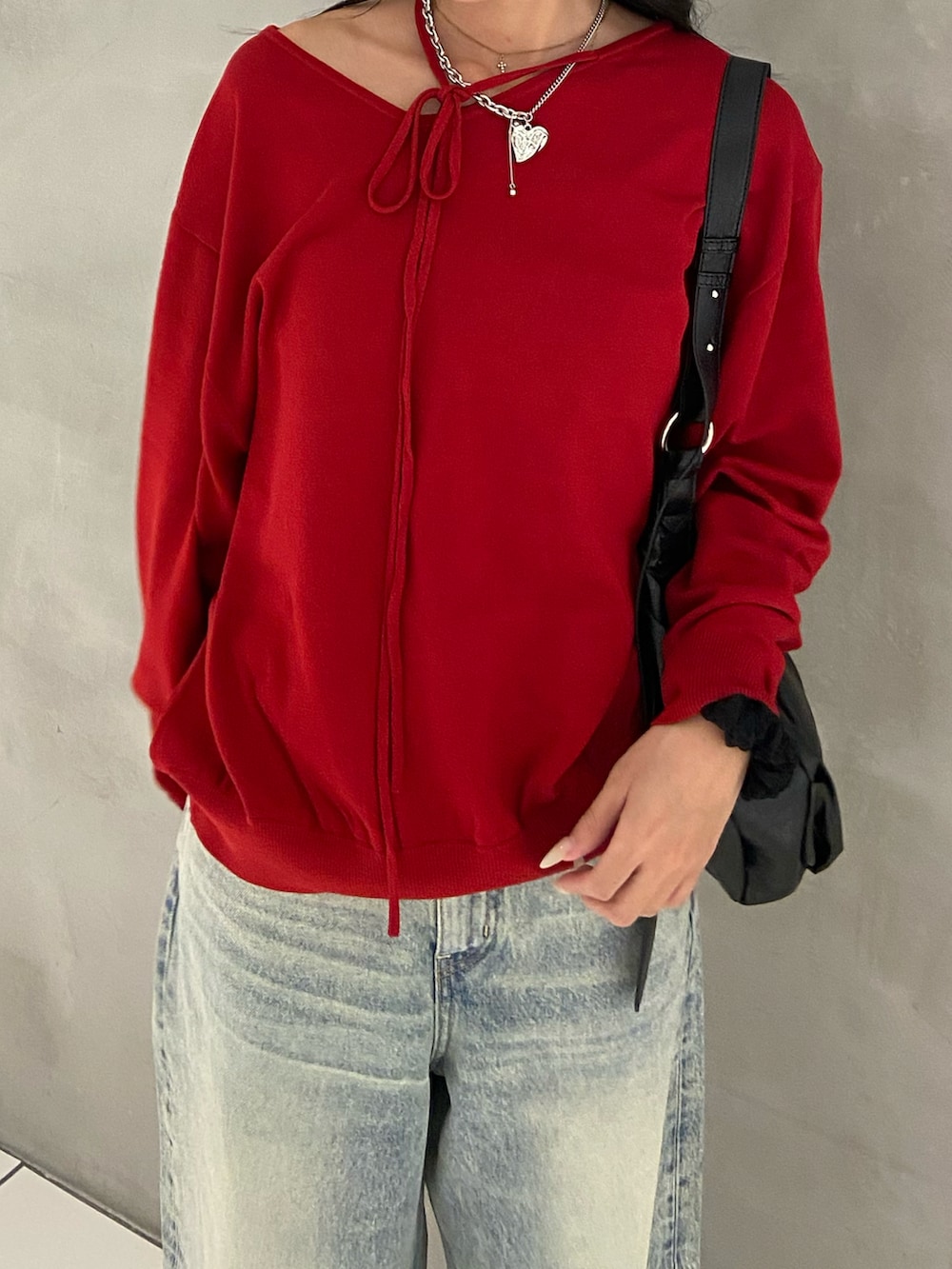 レッド系のニット/セーター、ブラック系のトートバッグ、ブルー系のデニムパンツを着用したレディースの秋コーディネートの2枚目の写真