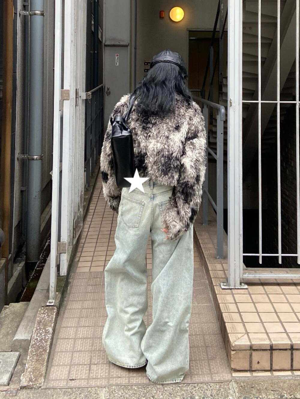 ブラック系のブルゾン、ブルー系のデニムパンツ、ブラック系のショルダーバッグを着用したレディースの秋コーディネートの2枚目の写真