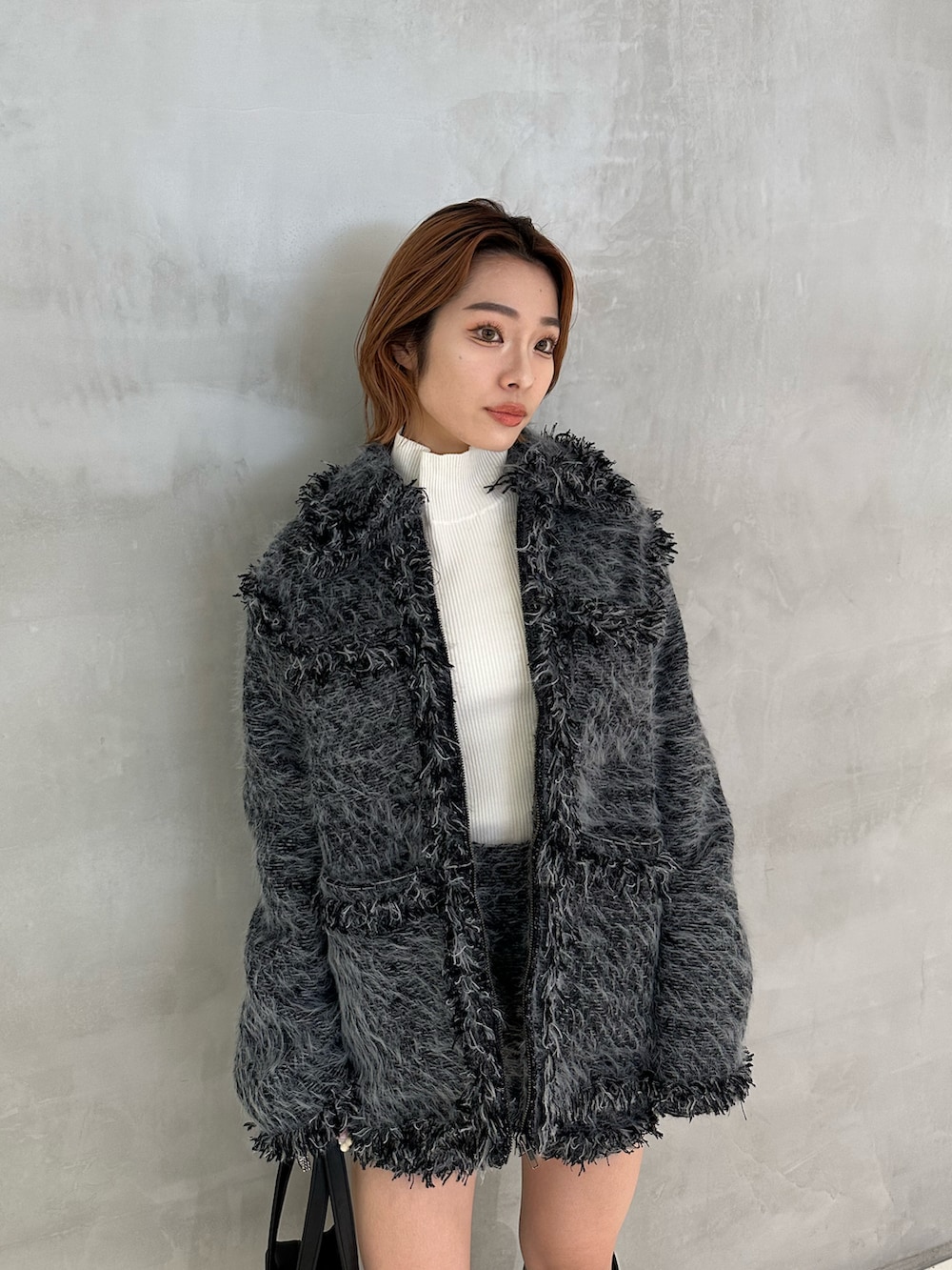 ホワイト系のニット/セーター、ブラック系のショルダーバッグ、ブラック系のブーツを着用したレディースの冬コーディネートの3枚目の写真