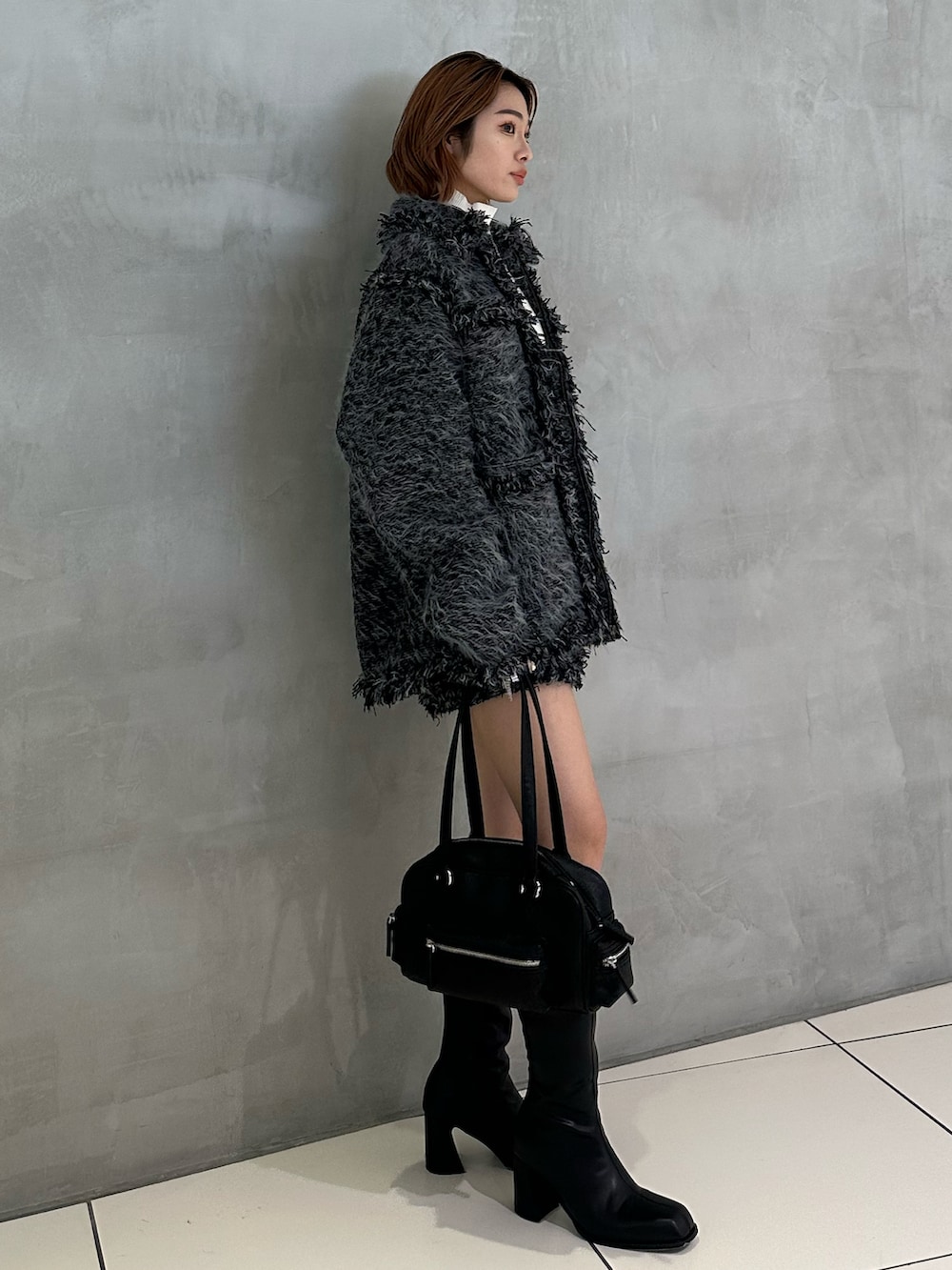 ホワイト系のニット/セーター、ブラック系のショルダーバッグ、ブラック系のブーツを着用したレディースの冬コーディネートの2枚目の写真