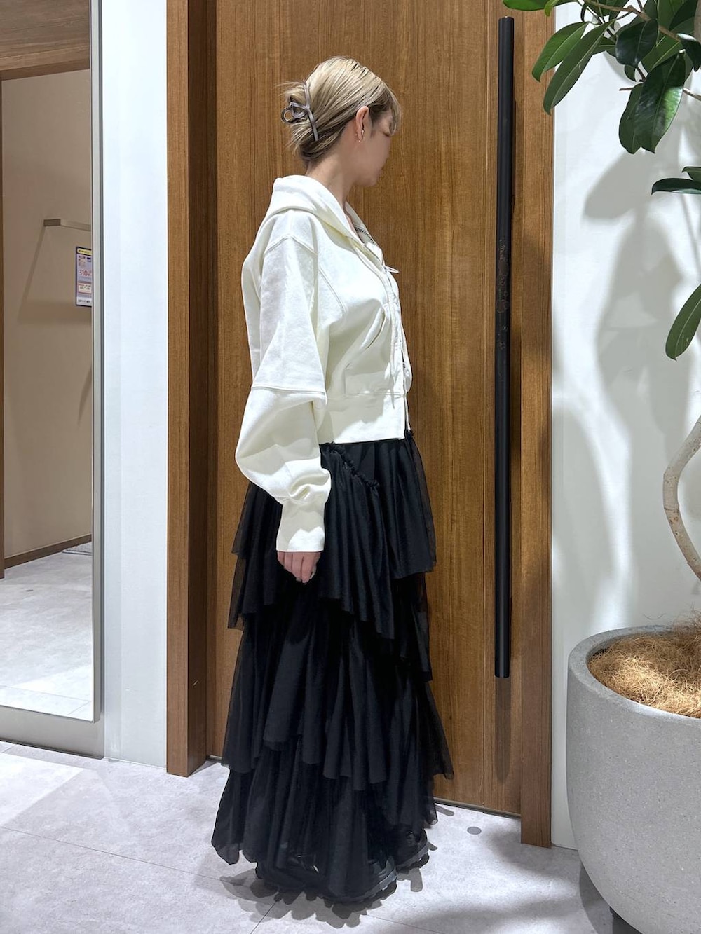 ブラック系のスカート、ベージュ系のパーカーを着用したレディースの春コーディネートの2枚目の写真