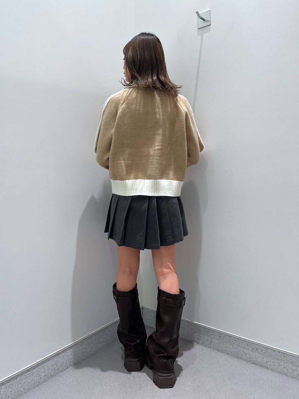 グレー系のスカート、ブラウン系のブーツ、ベージュ系のニット/セーターを着用したレディースの秋コーディネートの2枚目の写真