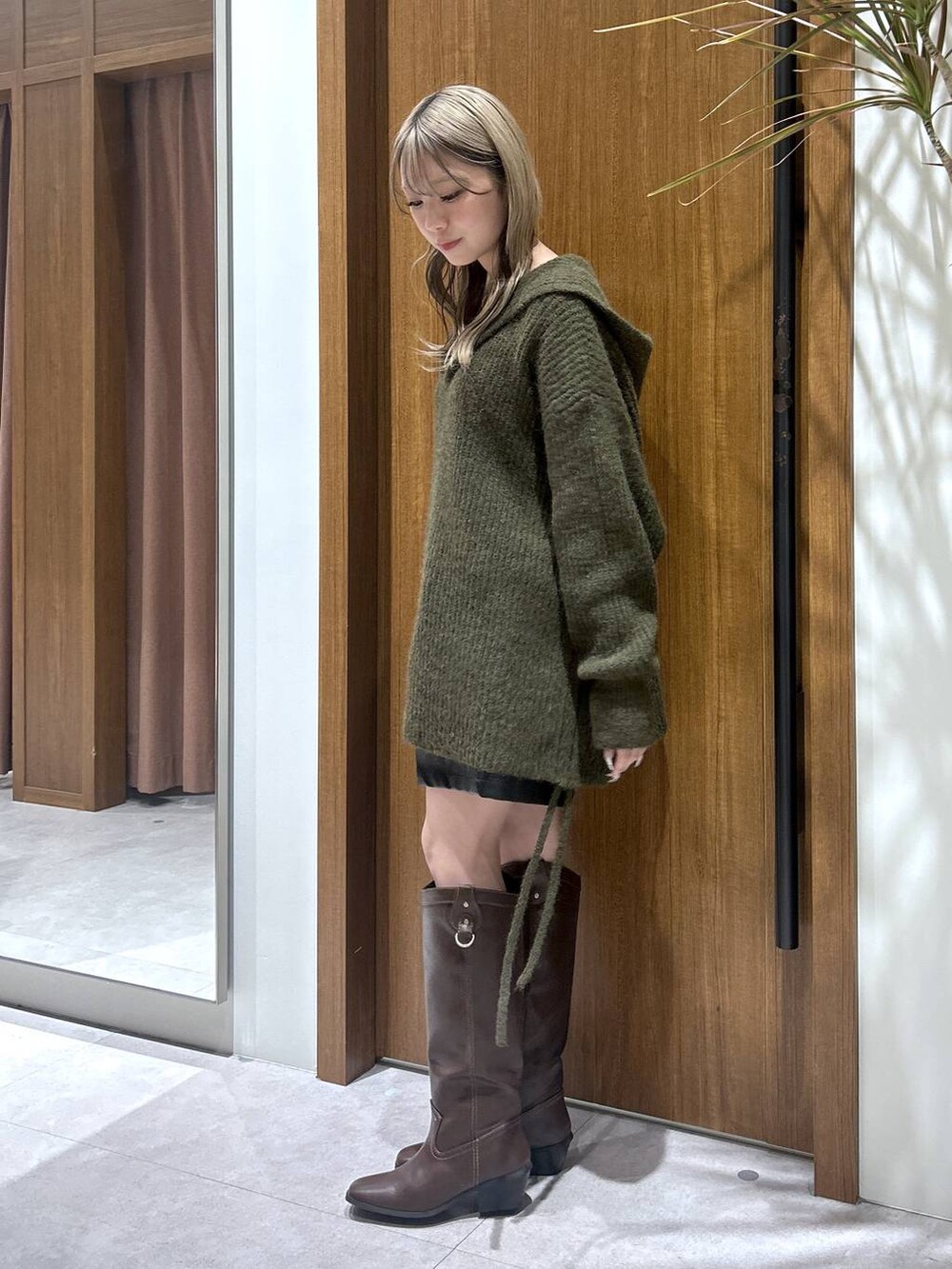 ブラウン系のブーツ、ブラック系のその他パンツ、グリーン系のニット/セーターを着用したレディースの冬コーディネートの2枚目の写真