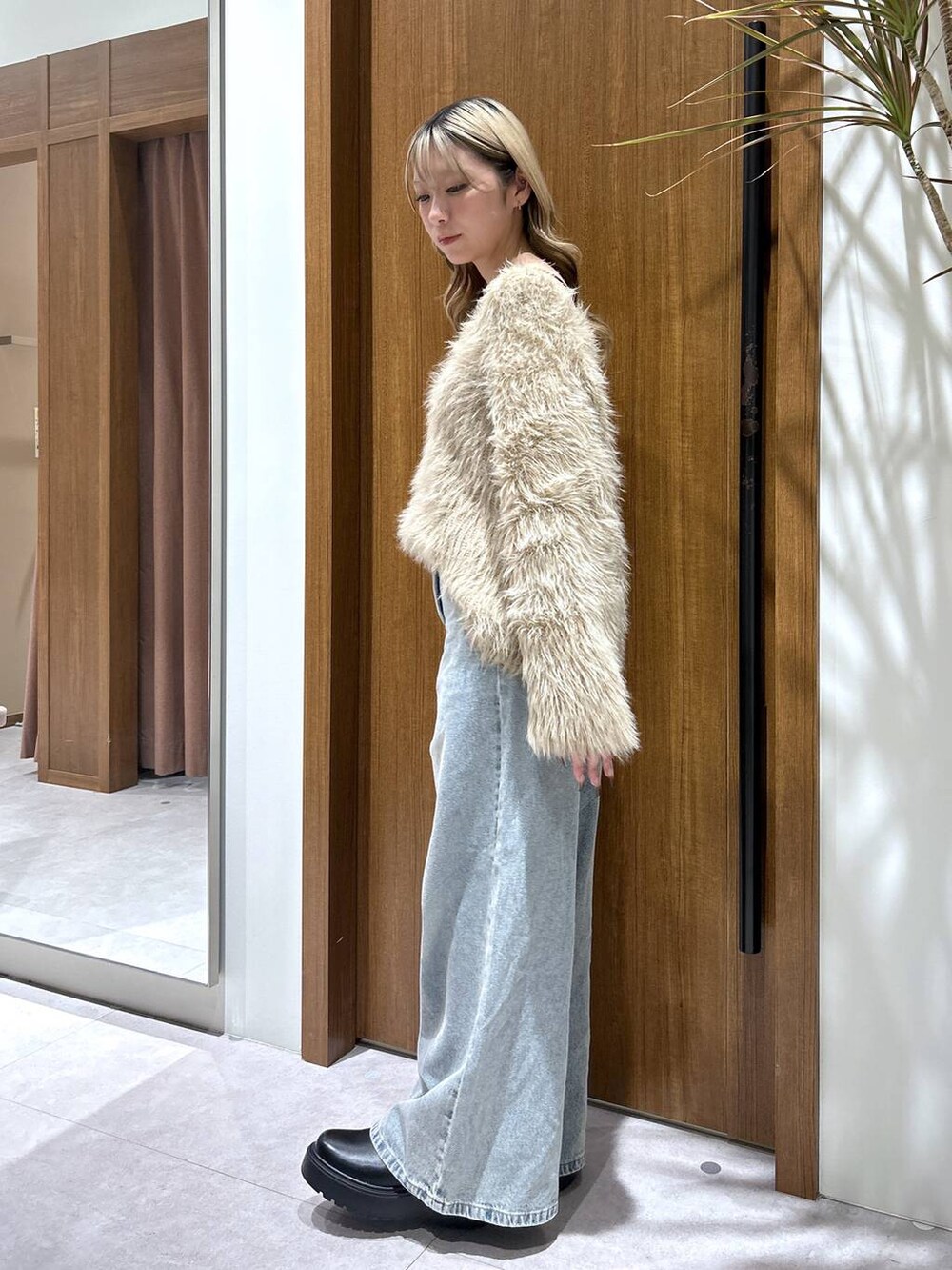 ブラック系のブーツ、ブルー系のデニムパンツ、ベージュ系のニット/セーターを着用したレディースの秋コーディネートの2枚目の写真