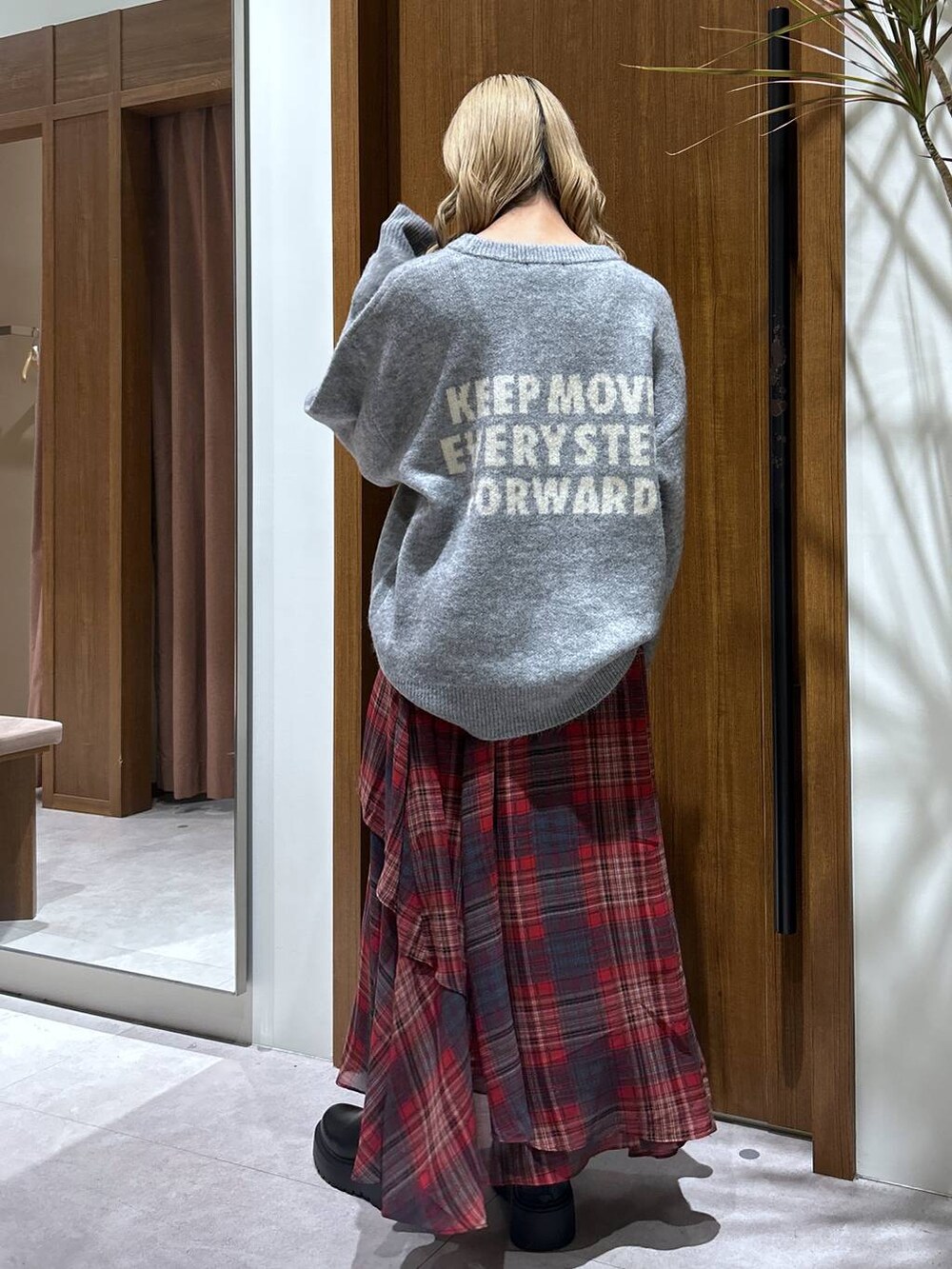 ブラック系のブーツ、グレー系のニット/セーター、レッド系のスカートを着用したレディースの秋コーディネートの3枚目の写真