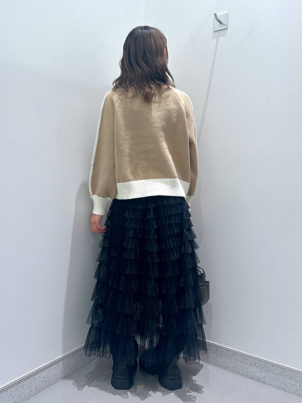 ブラウン系のショルダーバッグ、ブラック系のブーツ、ベージュ系のニット/セーターを着用したレディースの秋コーディネートの3枚目の写真