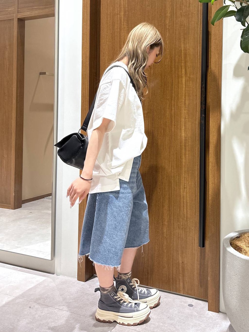 ブルー系のデニムパンツ、ブラック系のショルダーバッグ、ホワイト系のTシャツ/カットソーを着用したレディースの春コーディネートの2枚目の写真