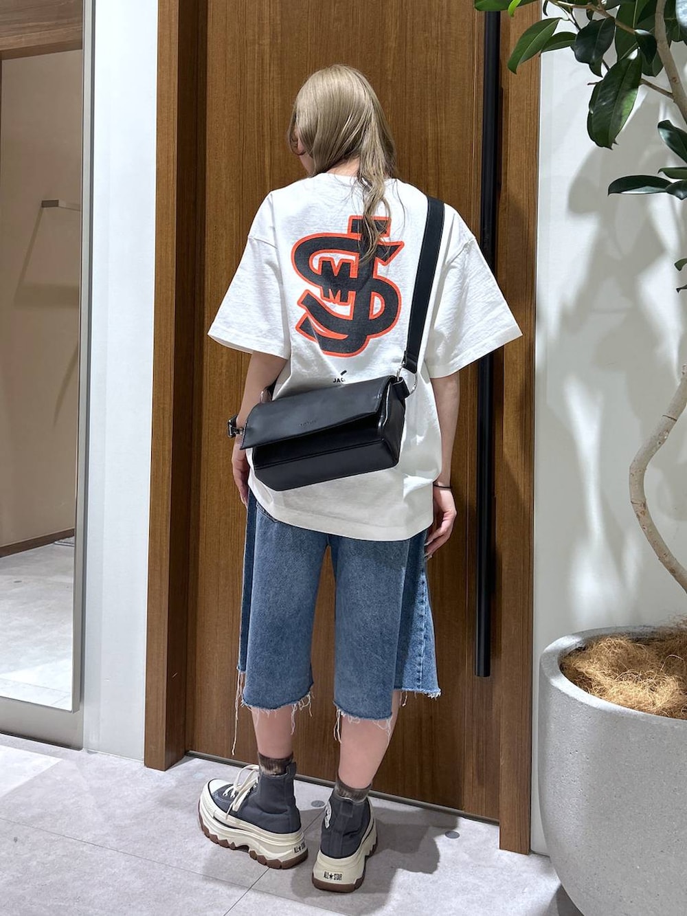 ブルー系のデニムパンツ、ブラック系のショルダーバッグ、ホワイト系のTシャツ/カットソーを着用したレディースの春コーディネートの3枚目の写真