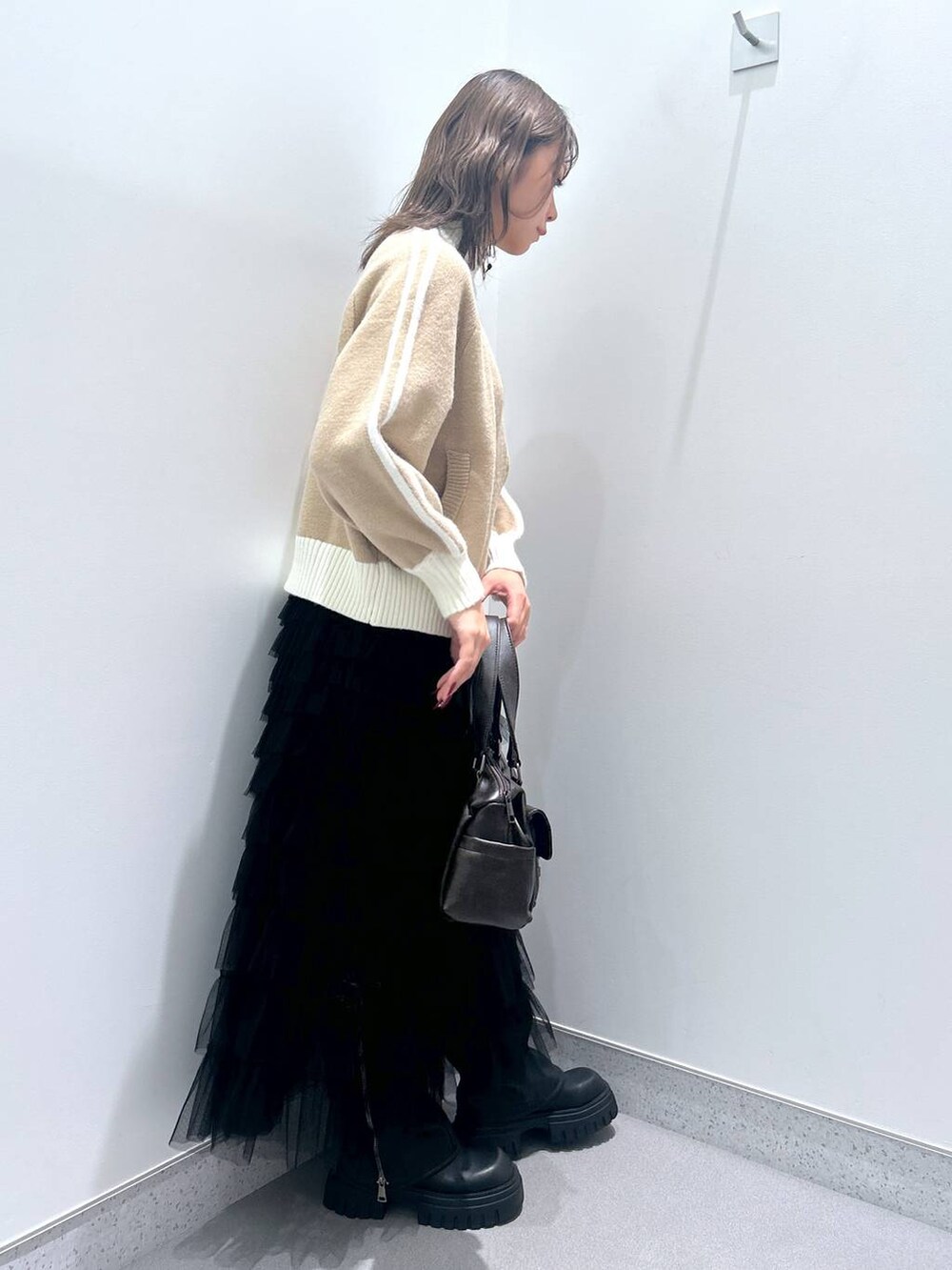 ブラウン系のショルダーバッグ、ブラック系のブーツ、ベージュ系のニット/セーターを着用したレディースの秋コーディネートの2枚目の写真