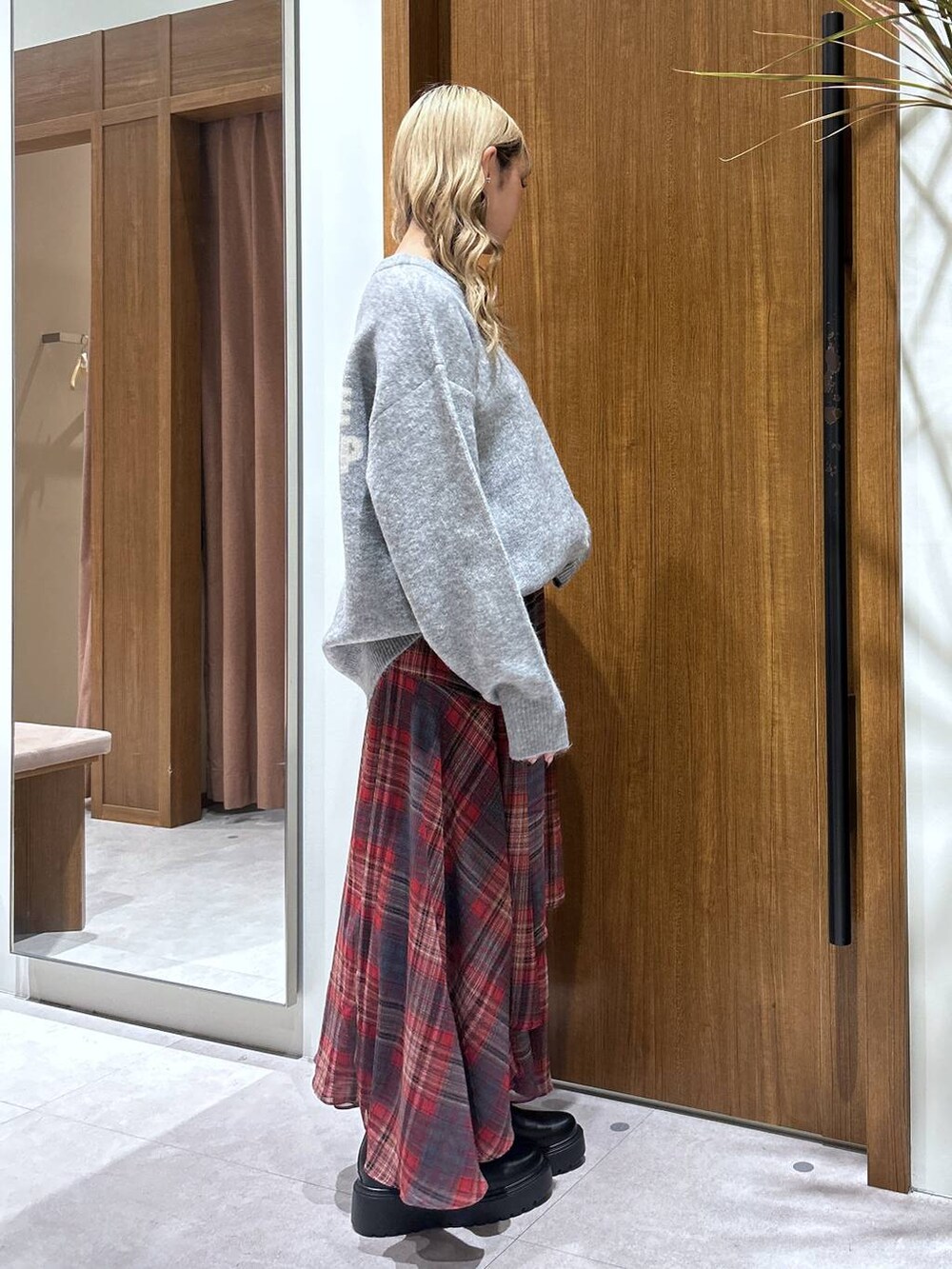 ブラック系のブーツ、グレー系のニット/セーター、レッド系のスカートを着用したレディースの秋コーディネートの2枚目の写真