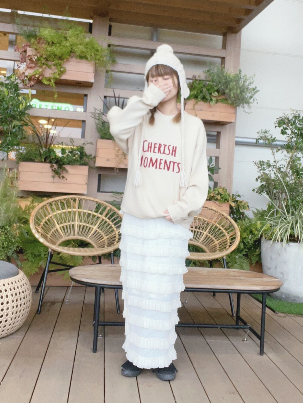 ホワイト系のニット/セーター、ホワイト系のスカート、ブラック系のスニーカーを着用したレディースの冬コーディネートの2枚目の写真