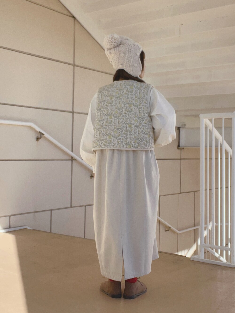 ホワイト系のベスト、ベージュ系のブーツ、ホワイト系のワンピース/ドレスを着用したレディースの冬コーディネートの3枚目の写真