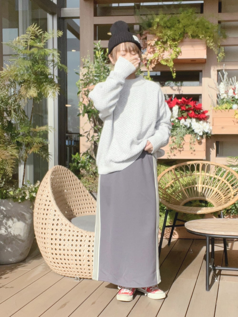 グレー系のスカート、レッド系のスニーカー、ホワイト系のニット/セーターを着用したレディースの冬コーディネートの2枚目の写真