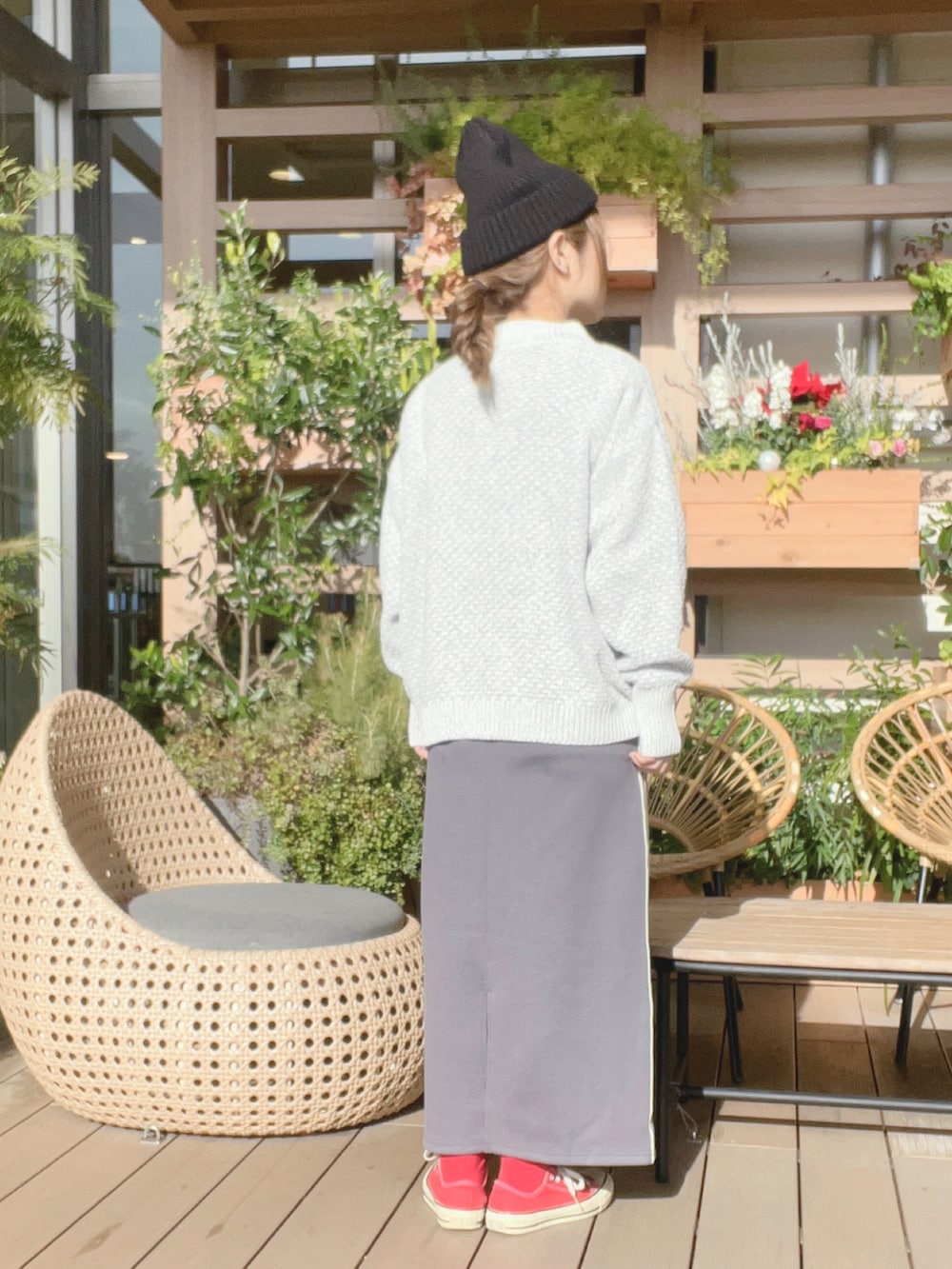 グレー系のスカート、レッド系のスニーカー、ホワイト系のニット/セーターを着用したレディースの冬コーディネートの3枚目の写真
