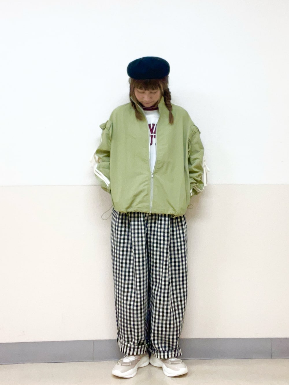 グリーン系のブルゾン、ホワイト系のパンツ、ベージュ系のスニーカーを着用したレディースの春コーディネートの2枚目の写真