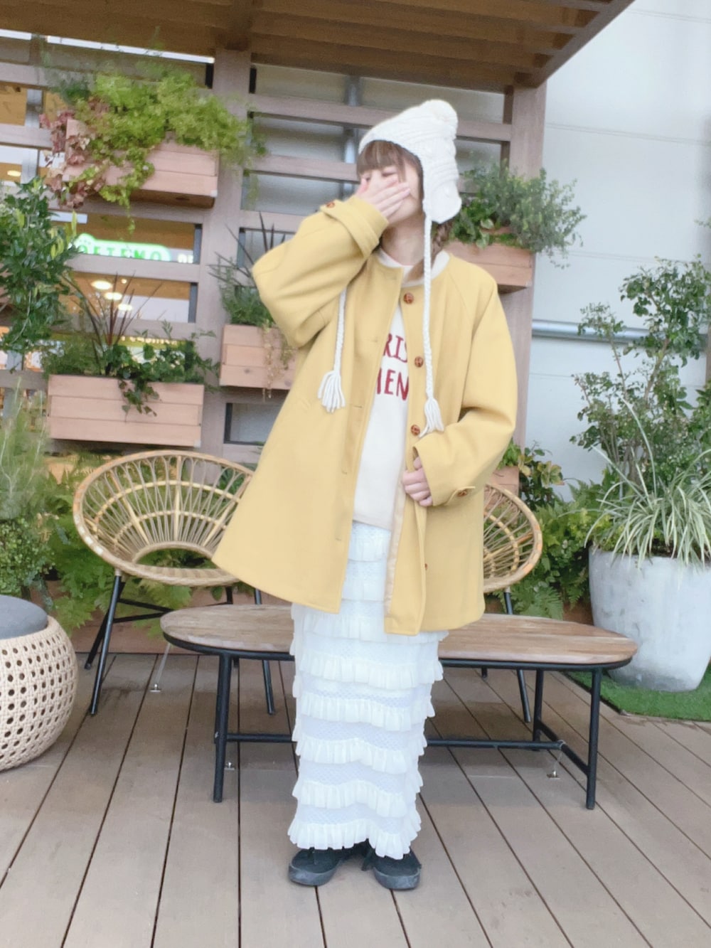 イエロー系のその他アウター、ホワイト系のニット/セーター、ホワイト系のスカートを着用したレディースの冬コーディネートの2枚目の写真