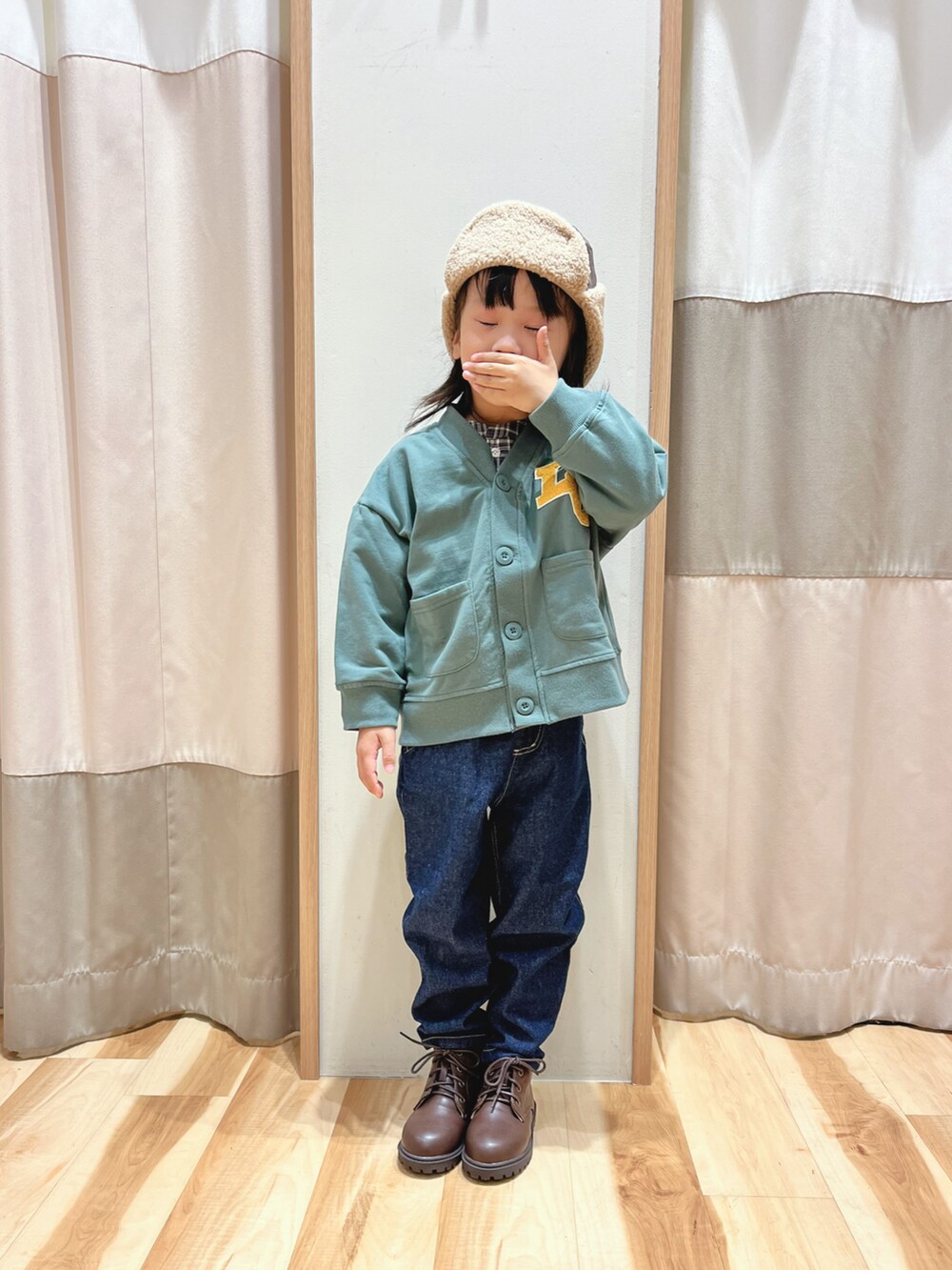 グリーン系のカーディガン/ボレロ、ブルー系のデニムパンツ、ブラウン系のブーツを着用したレディースの秋コーディネートの2枚目の写真