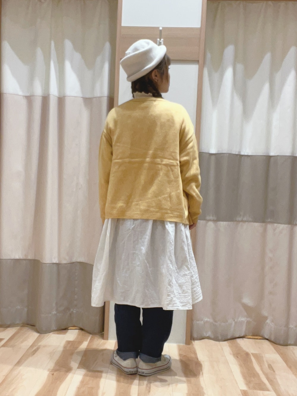 イエロー系のカーディガン/ボレロ、ホワイト系のニット/セーター、ホワイト系のチュニックを着用したレディースの冬コーディネートの3枚目の写真