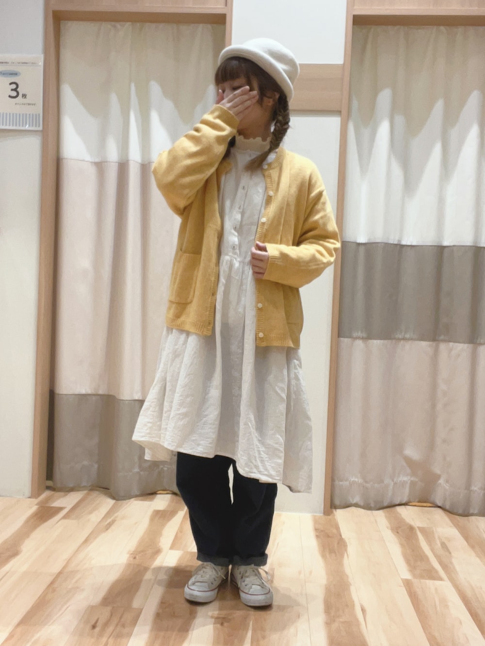 イエロー系のカーディガン/ボレロ、ホワイト系のニット/セーター、ホワイト系のチュニックを着用したレディースの冬コーディネートの2枚目の写真