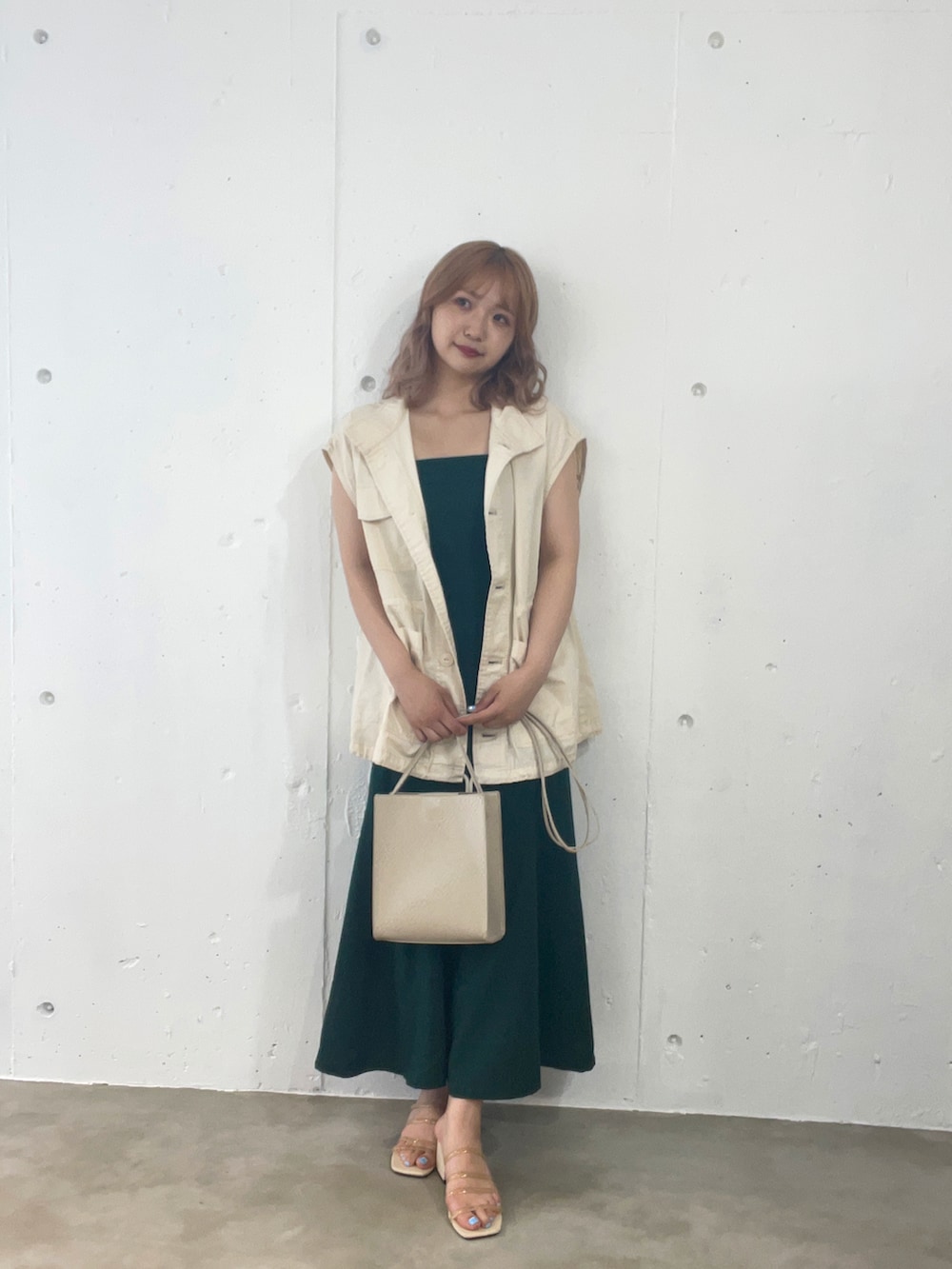 ホワイト系のベスト、グリーン系のジャンパースカート、ベージュ系のサンダルを着用したレディースの夏コーディネートの2枚目の写真
