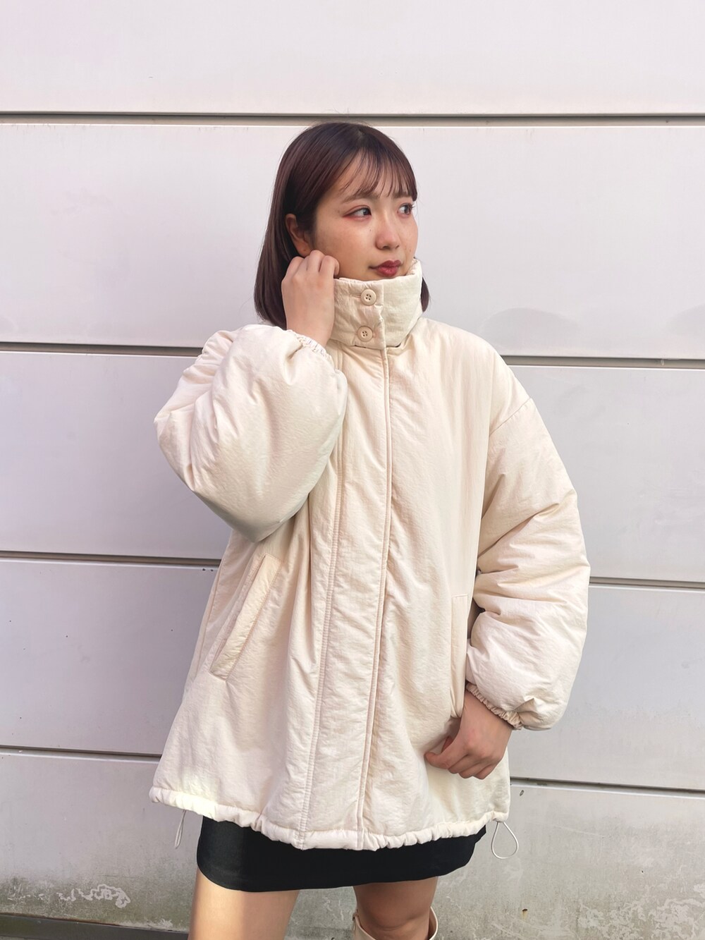 ホワイト系のブルゾン、ブラック系のスカート、ホワイト系のブーツを着用したレディースの冬コーディネートの3枚目の写真