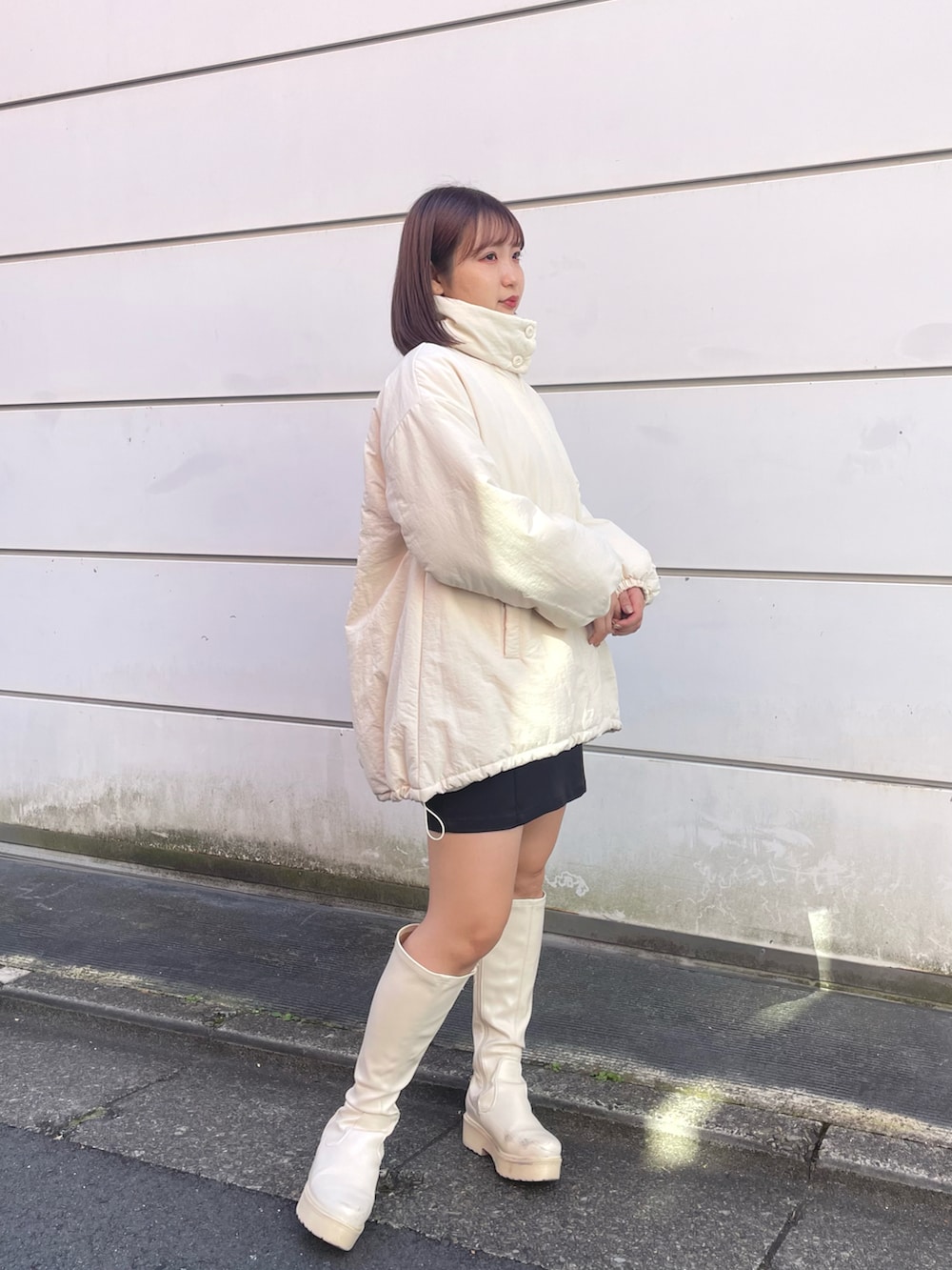 ホワイト系のブルゾン、ブラック系のスカート、ホワイト系のブーツを着用したレディースの冬コーディネートの2枚目の写真