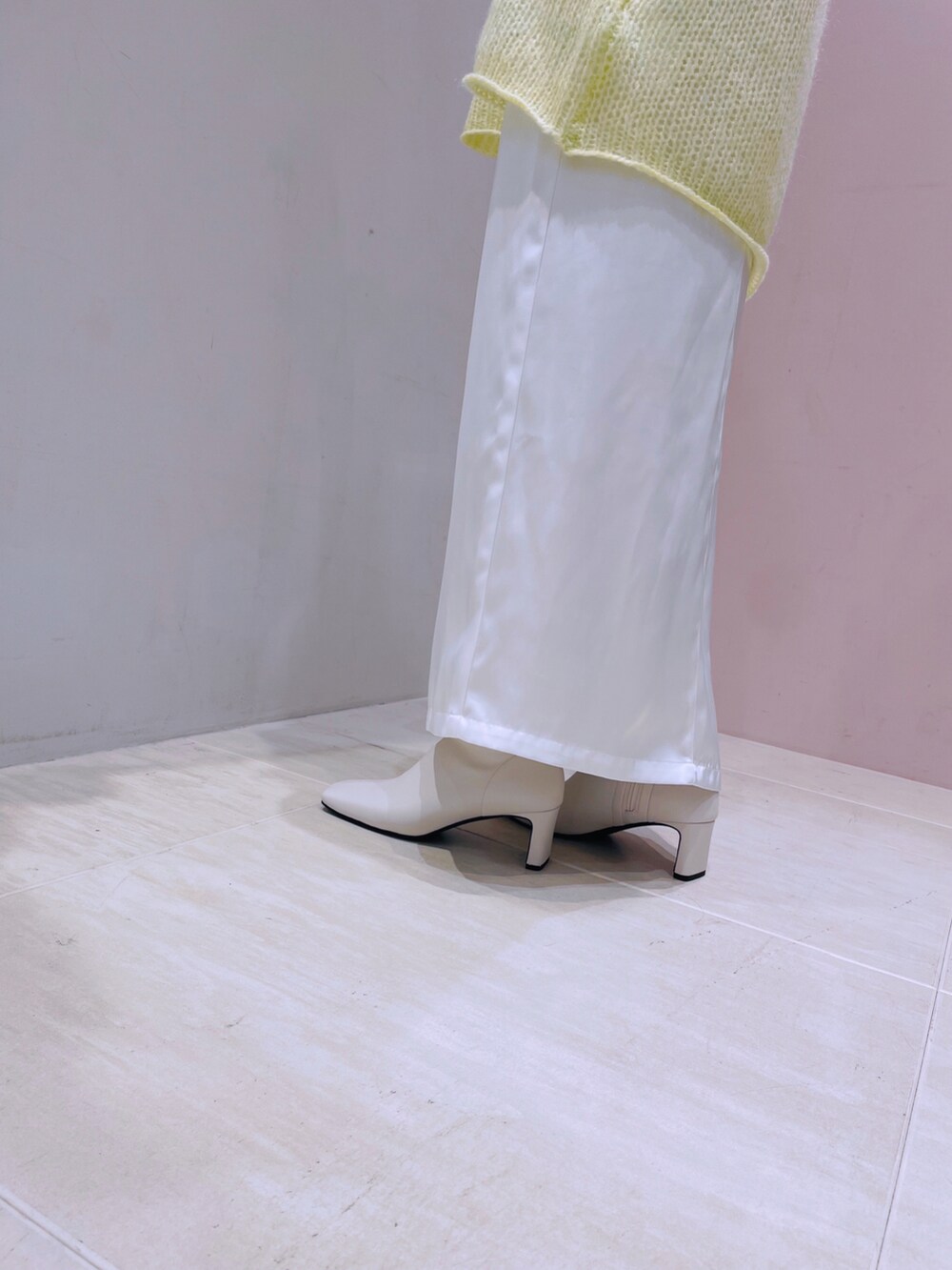 イエロー系のニット/セーター、ホワイト系のブーツを着用したレディースの秋コーディネートの2枚目の写真