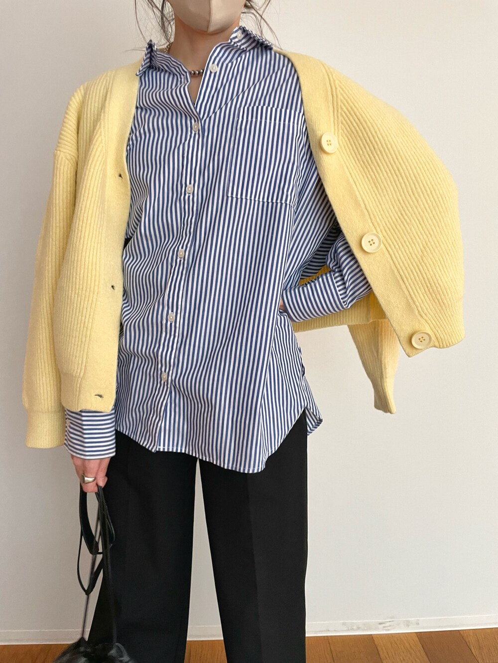 ブラック系のパンツ、ブルー系のシャツ/ブラウス、イエロー系のカーディガン/ボレロを着用したレディースの春コーディネートの2枚目の写真