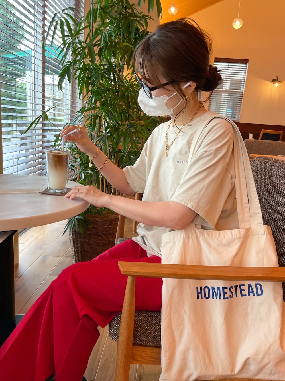 レッド系のスラックス、ブラック系のサンダル、ホワイト系のトートバッグを着用したレディースの夏コーディネートの3枚目の写真