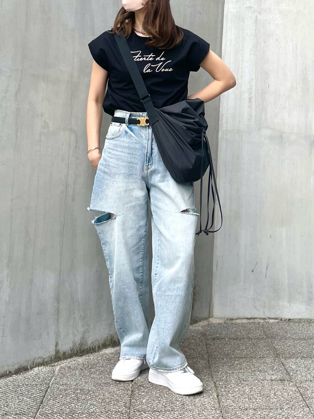 ブルー系のデニムパンツ、ブラック系のバッグ、ブラック系のTシャツ/カットソーを着用したレディースの春コーディネートの2枚目の写真