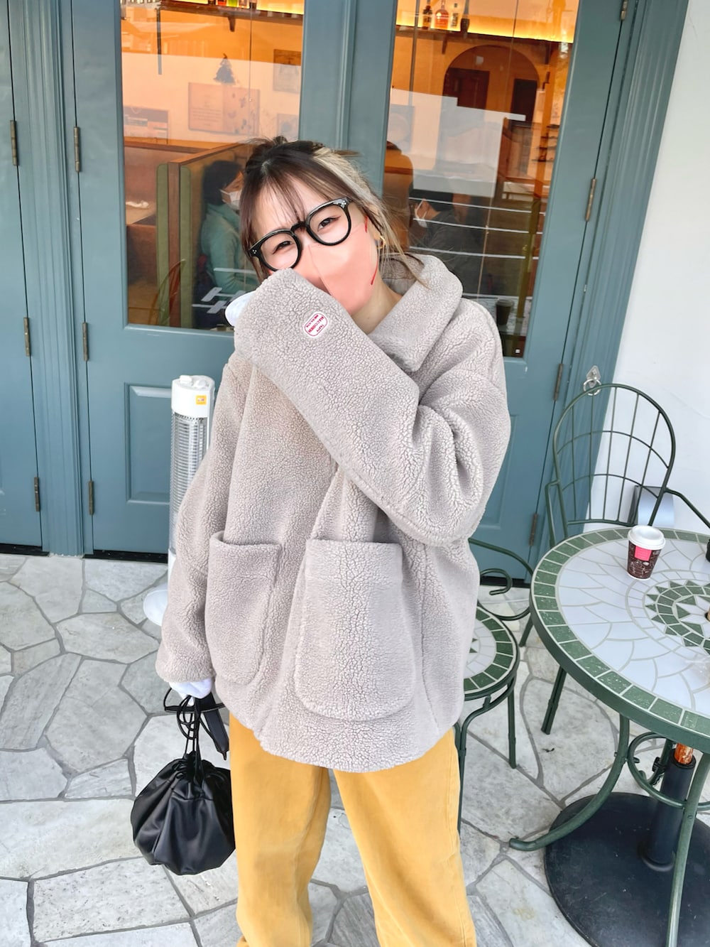 イエロー系のパンツ、ベージュ系のその他アウター、ホワイト系のショルダーバッグを着用したレディースの冬コーディネートの3枚目の写真