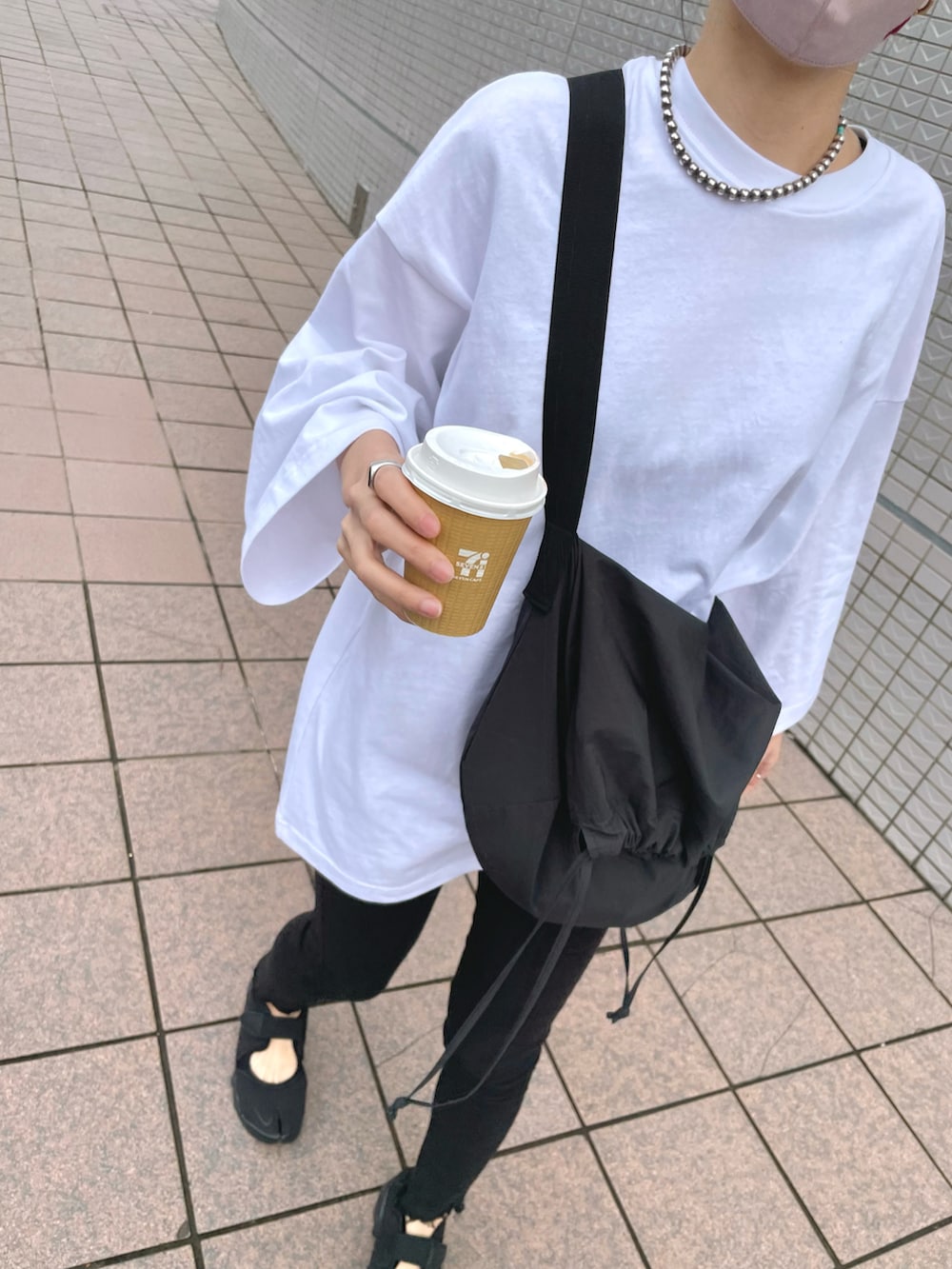 ブラック系のバッグ、ブラック系のサンダル、ホワイト系のTシャツ/カットソーを着用したレディースの春コーディネートの2枚目の写真