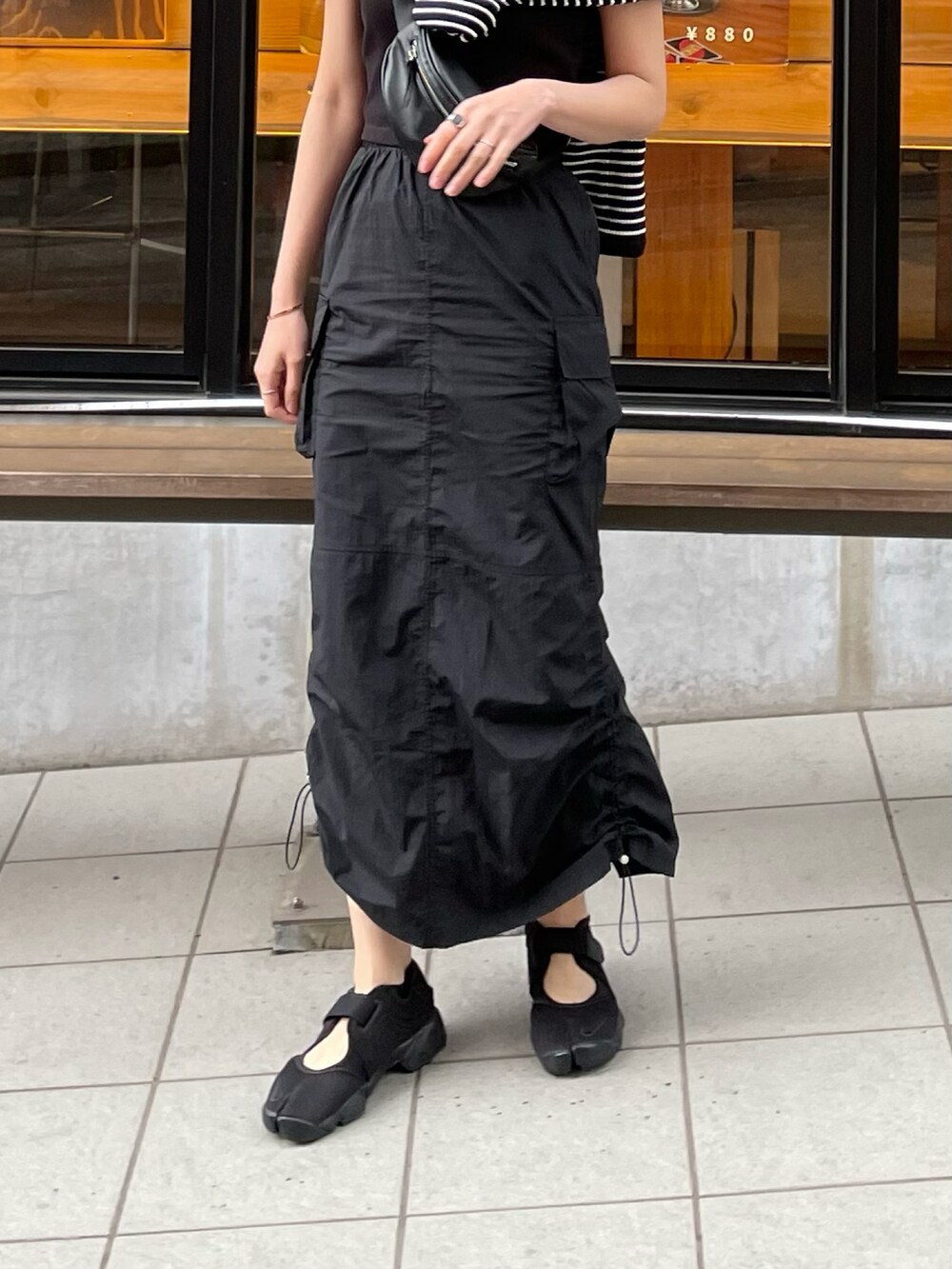 ブラック系のスカート、ブラック系のボディバッグ/ウエストポーチ、ブラック系のサンダルを着用したレディースの春コーディネートの3枚目の写真