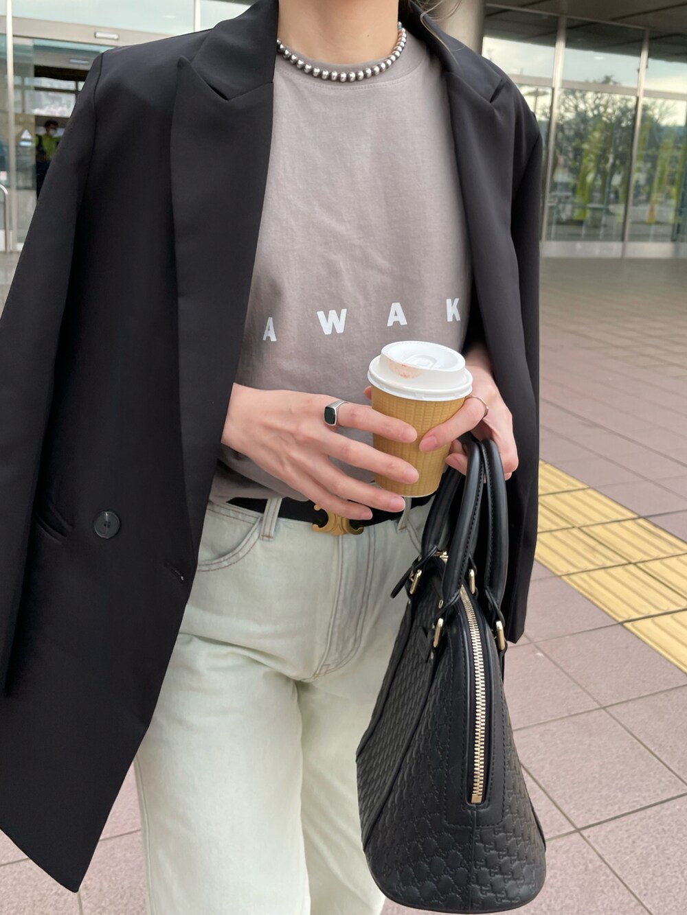 ブルー系のデニムパンツ、ベージュ系のTシャツ/カットソー、ブラック系のバッグを着用したレディースの春コーディネートの3枚目の写真