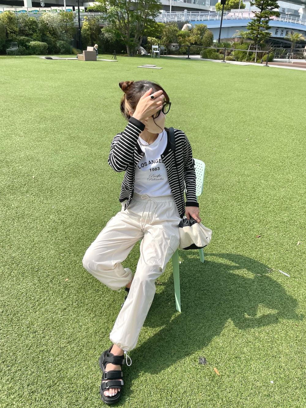 ホワイト系のショルダーバッグ、ホワイト系のTシャツ/カットソー、ブラック系のカーディガン/ボレロを着用したレディースの夏コーディネートの4枚目の写真