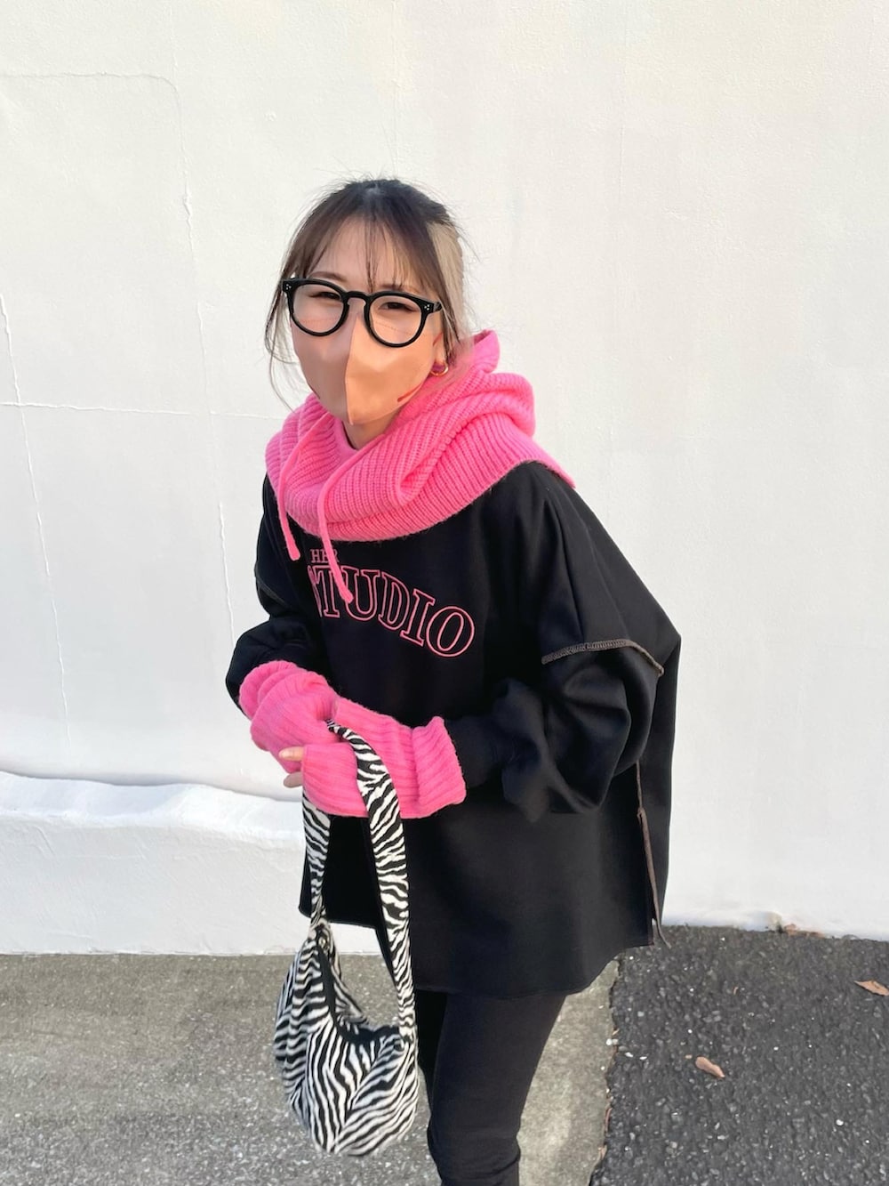 ブラック系のスウェット、ブラック系のブーツ、ピンク系のアームカバーを着用したレディースの冬コーディネートの2枚目の写真