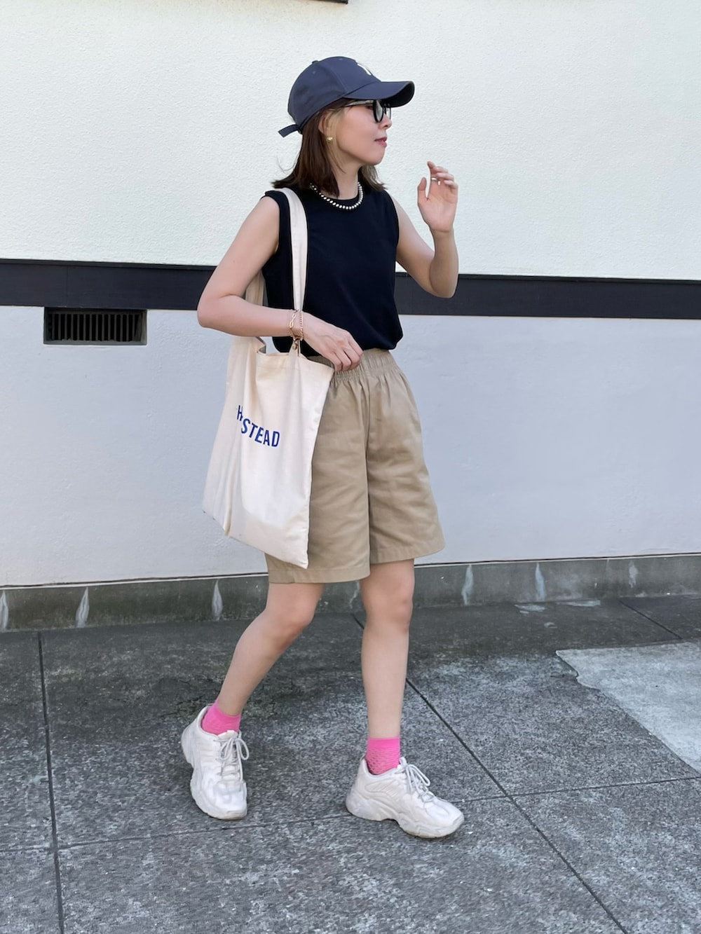 ホワイト系のトートバッグ、ブラック系のTシャツ/カットソー、ベージュ系のスニーカーを着用したレディースの夏コーディネートの2枚目の写真