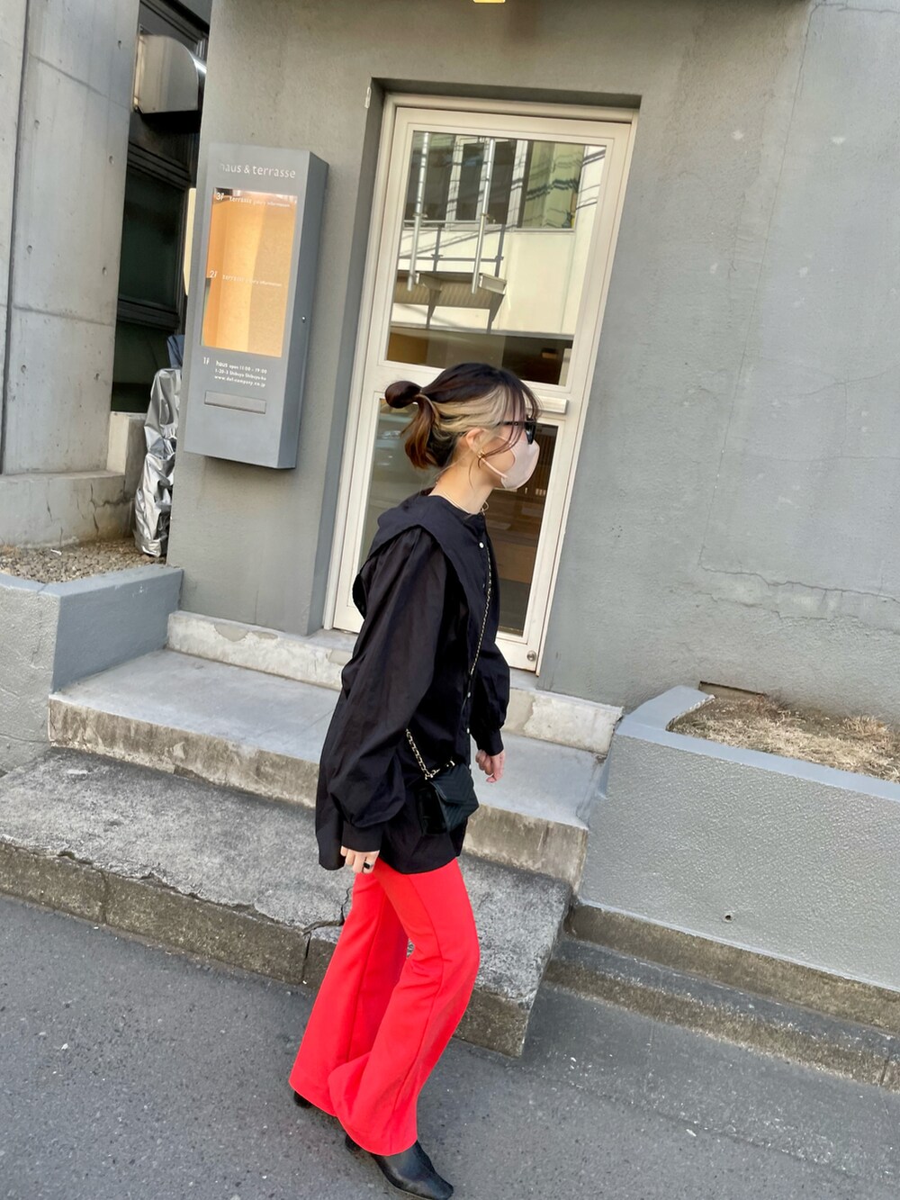 ブラック系のシャツ/ブラウス、オレンジ系のパンツを着用したレディースの春コーディネートの2枚目の写真