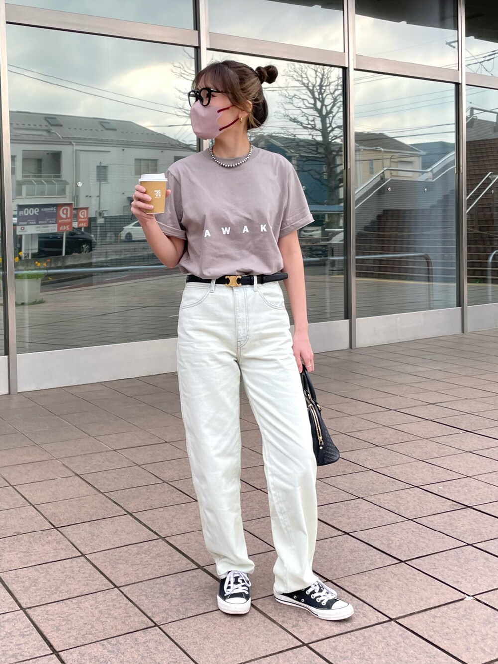 ブルー系のデニムパンツ、ベージュ系のTシャツ/カットソー、ブラック系のバッグを着用したレディースの春コーディネートの2枚目の写真