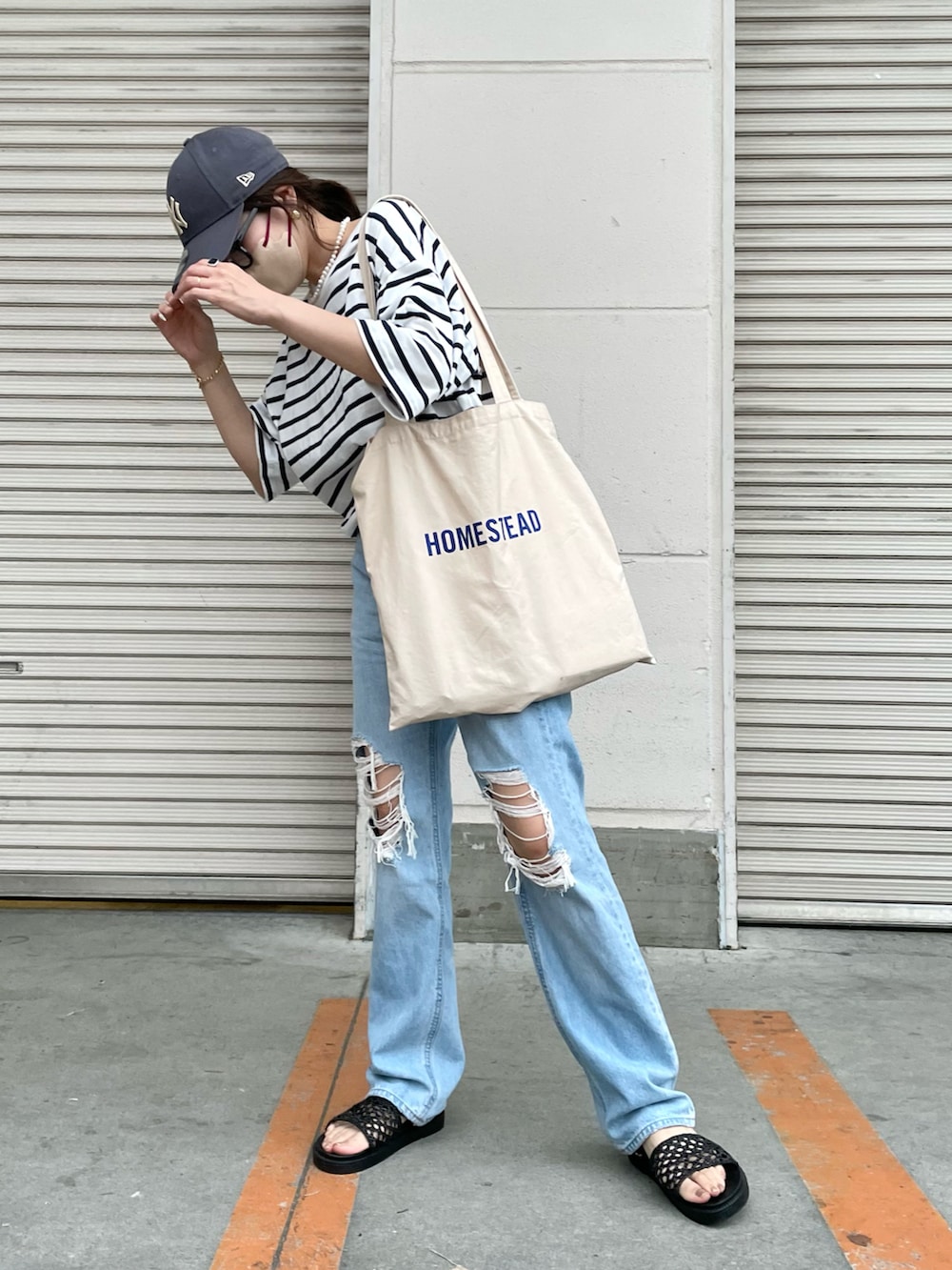ブルー系のデニムパンツ、ブルー系のTシャツ/カットソー、ホワイト系のトートバッグを着用したレディースの夏コーディネートの2枚目の写真